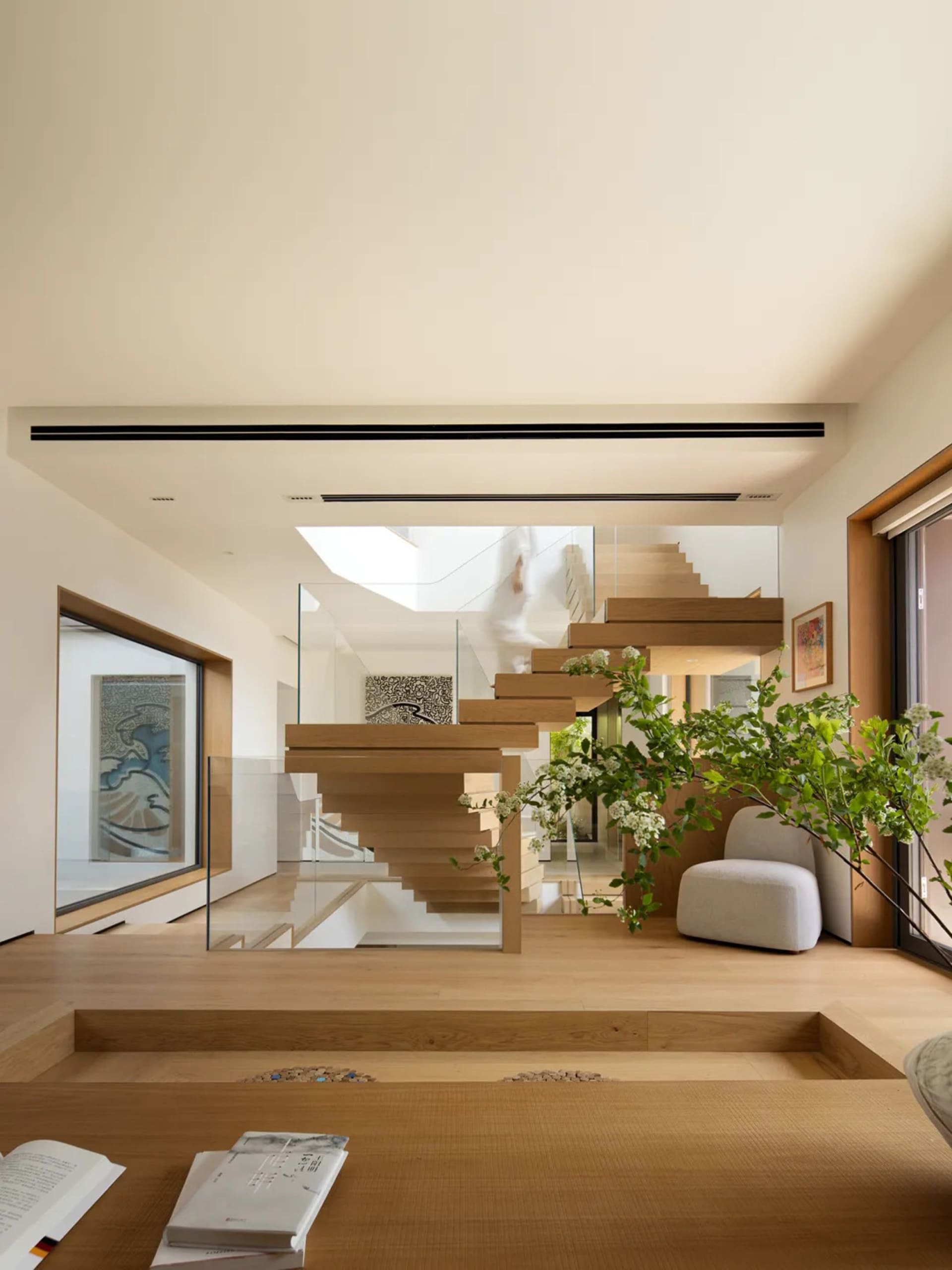 A modern residential interior featuring a sleek, minimalist staircase made of wood and glass.