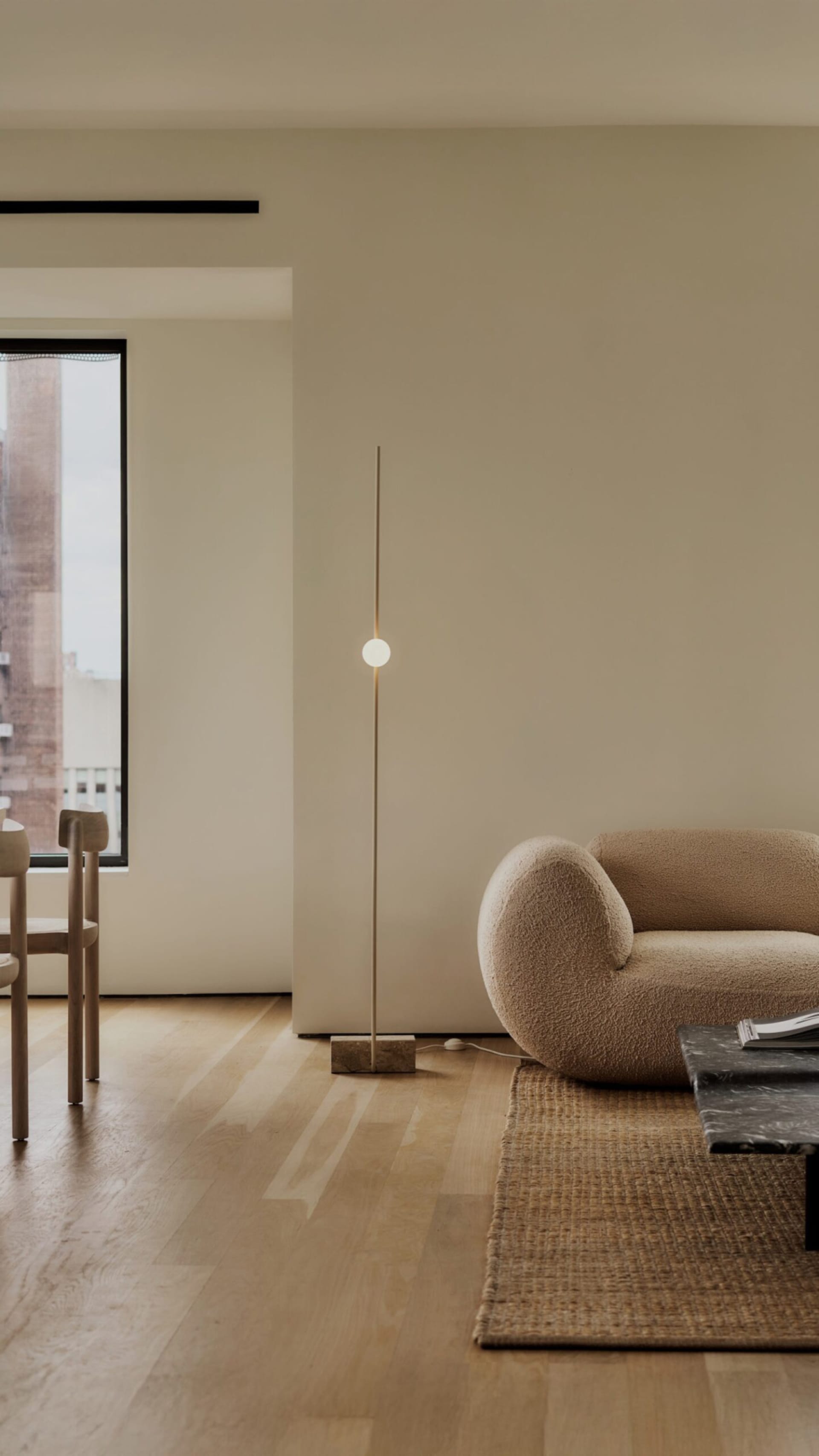 A minimalist living room with a wooden floor, a beige carpet, and a marble coffee table.