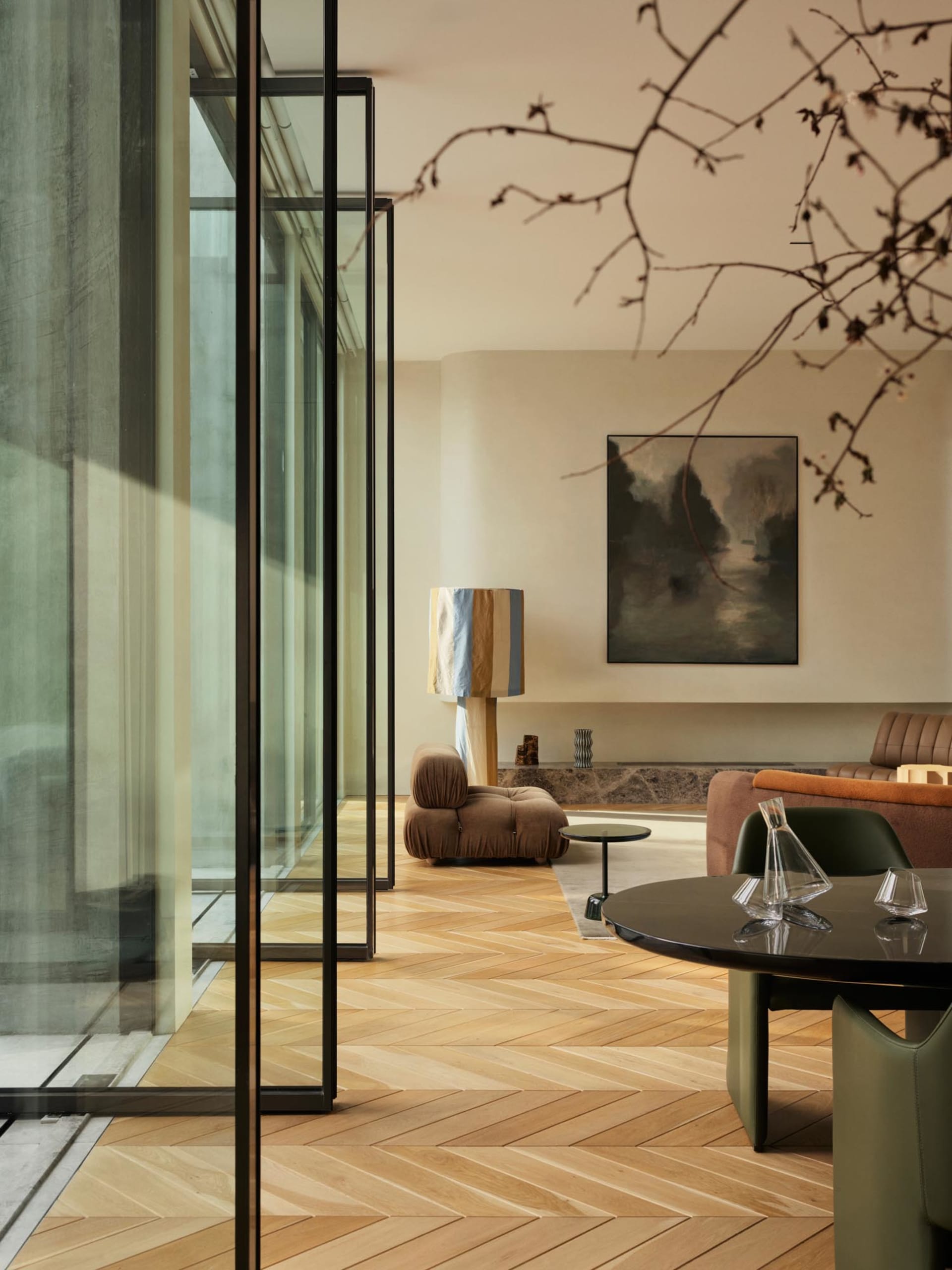 A modern minimalist living room featuring wooden flooring, a round table, and a comfortable seating arrangement.