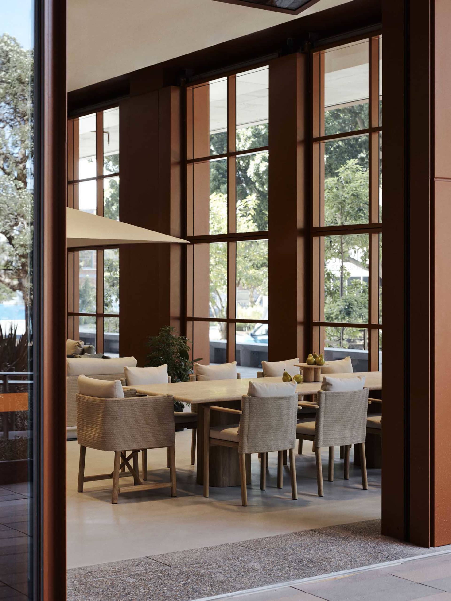 Modern restaurant interior with a long wooden dining table, stone countertops, and contemporary design elements.
