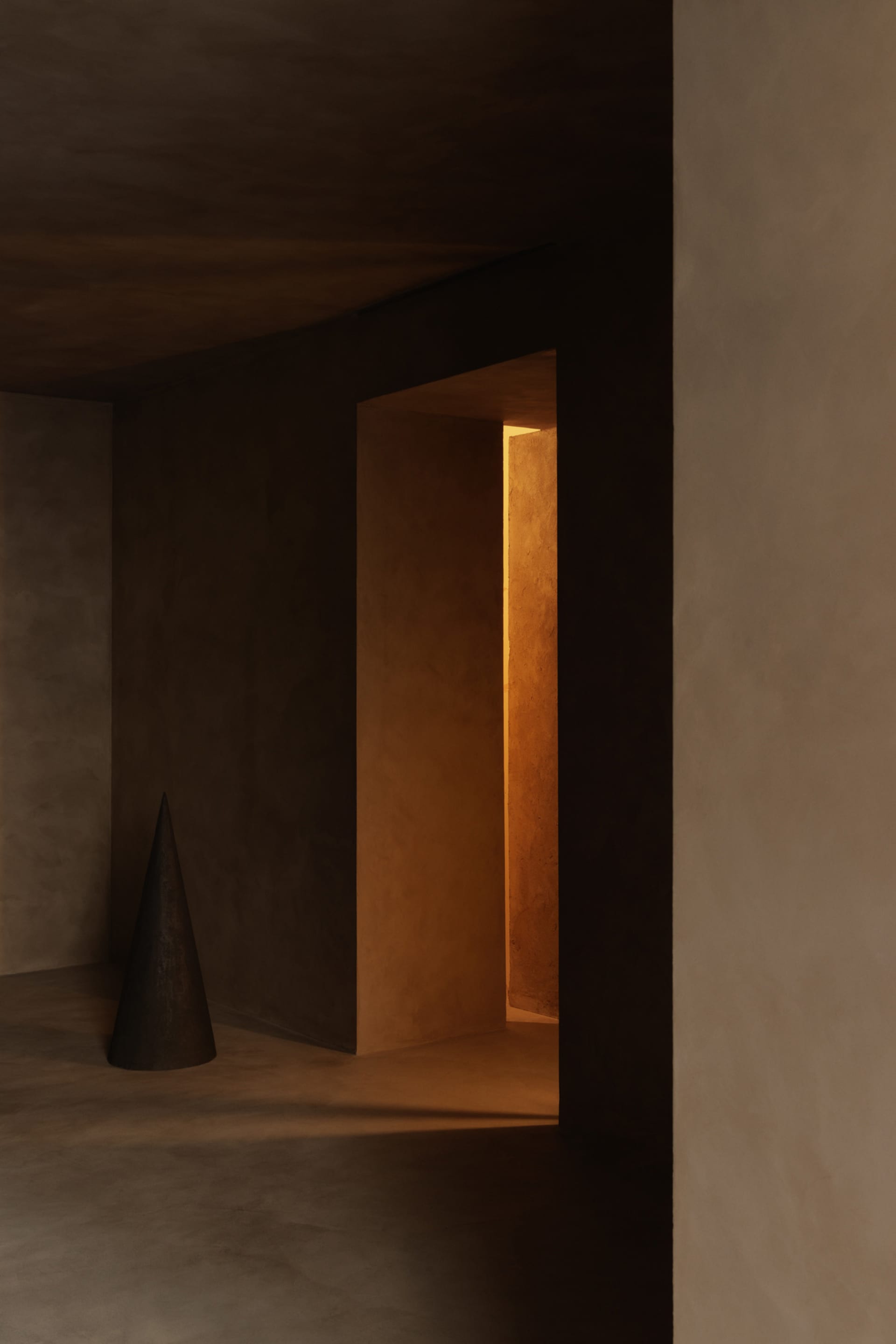 A minimalist hallway with smooth concrete walls and floor, illuminated by warm, natural light.