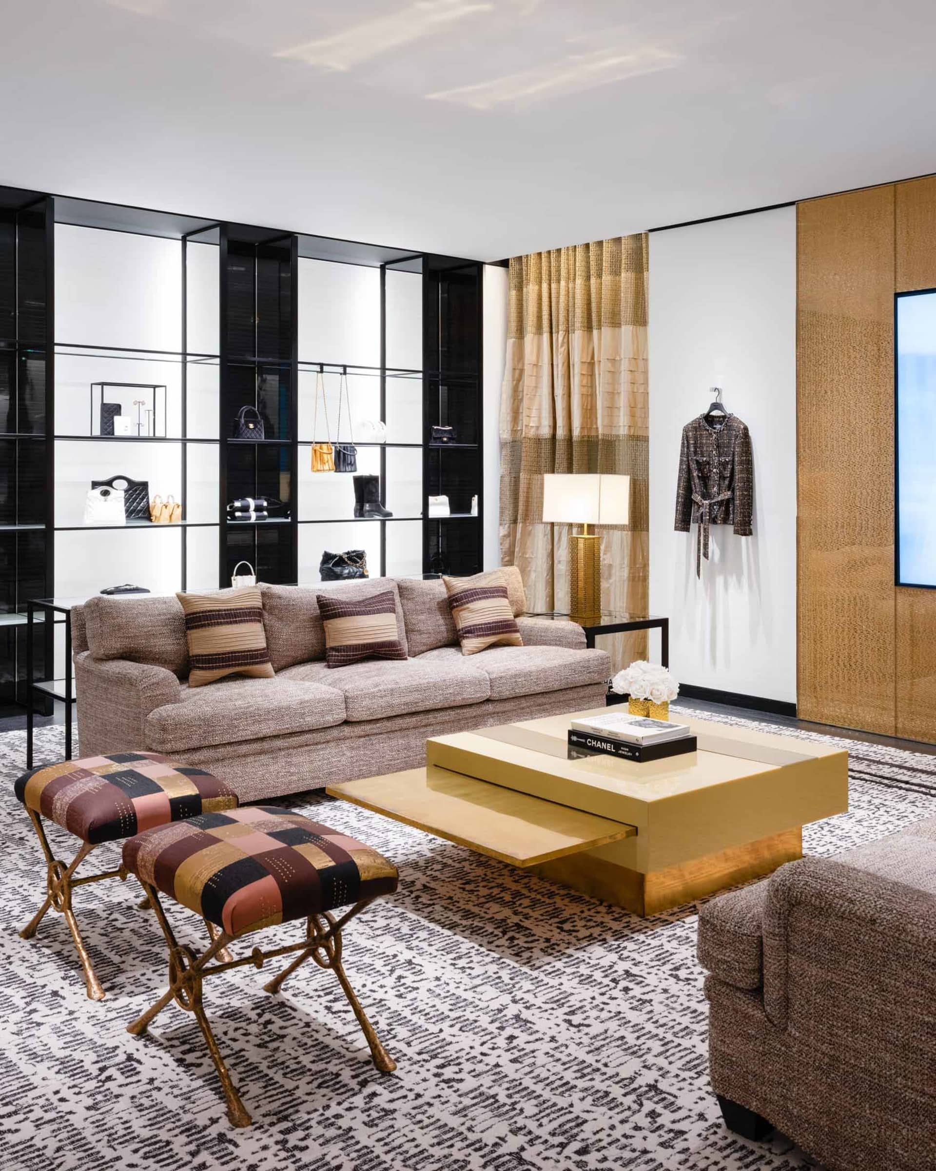 A modern living room featuring a beige couch, yellow coffee table, and glass shelves displaying various fashion items.
