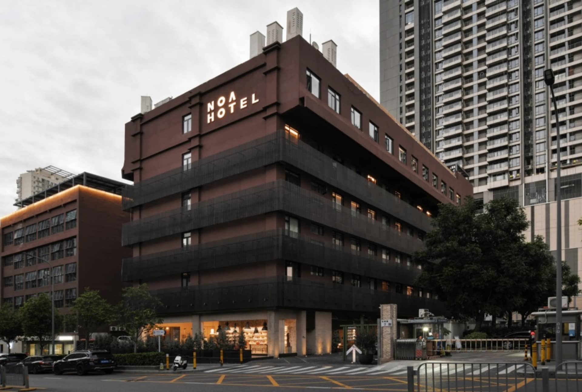 一座擁有磚牆外觀的現代旅館建築，搭配燈光照亮的招牌。