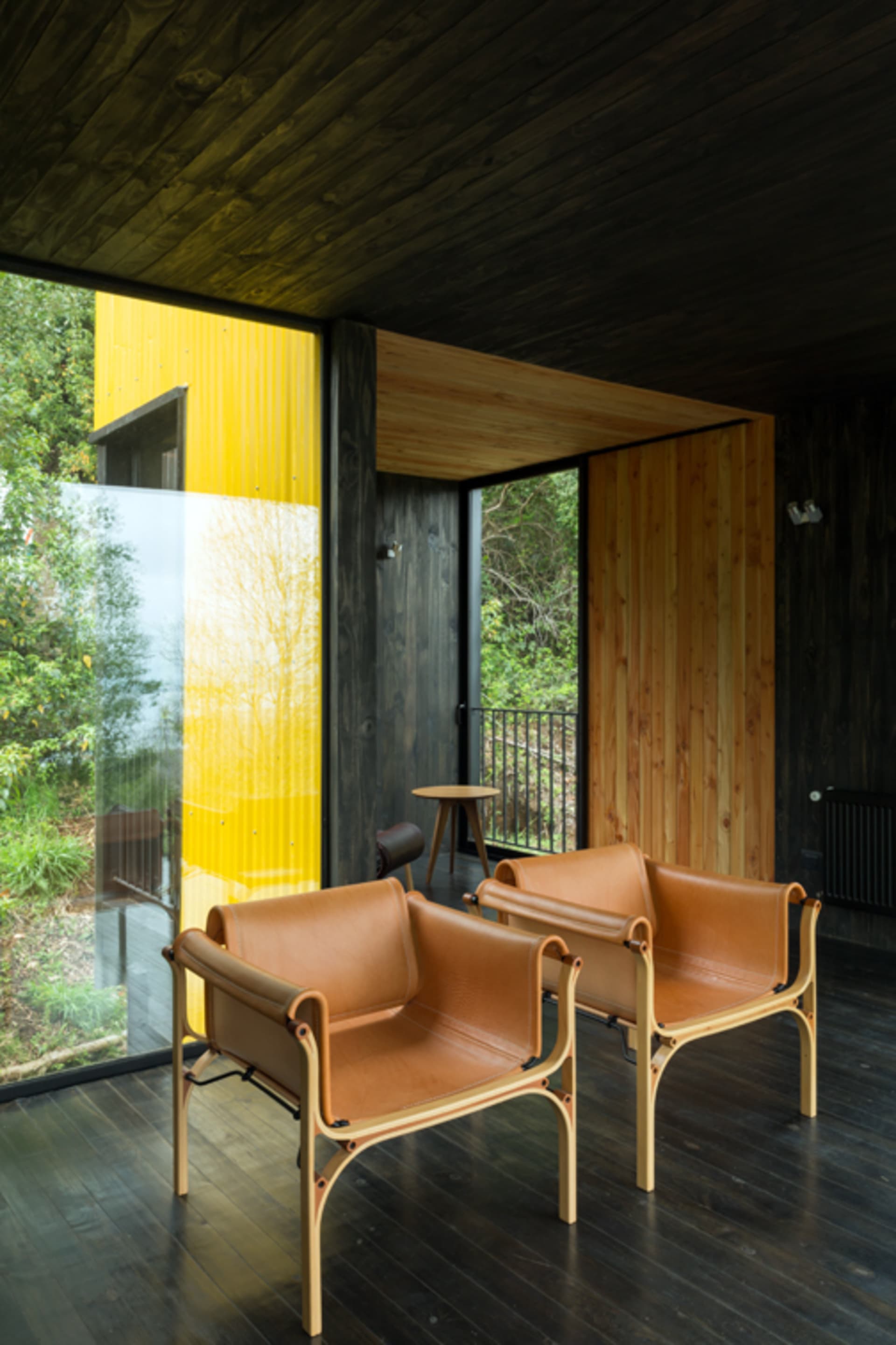 A modern interior design featuring a living room with leather furniture and a dark wooden floor.