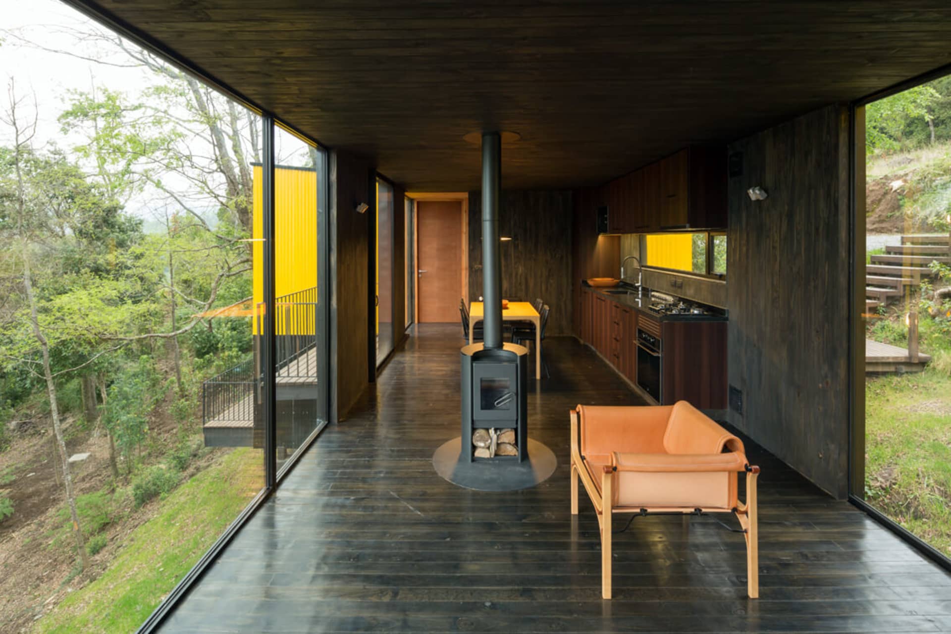Industrial-style residential interior with wooden floor, metal kitchen, and leather lounge chair.
