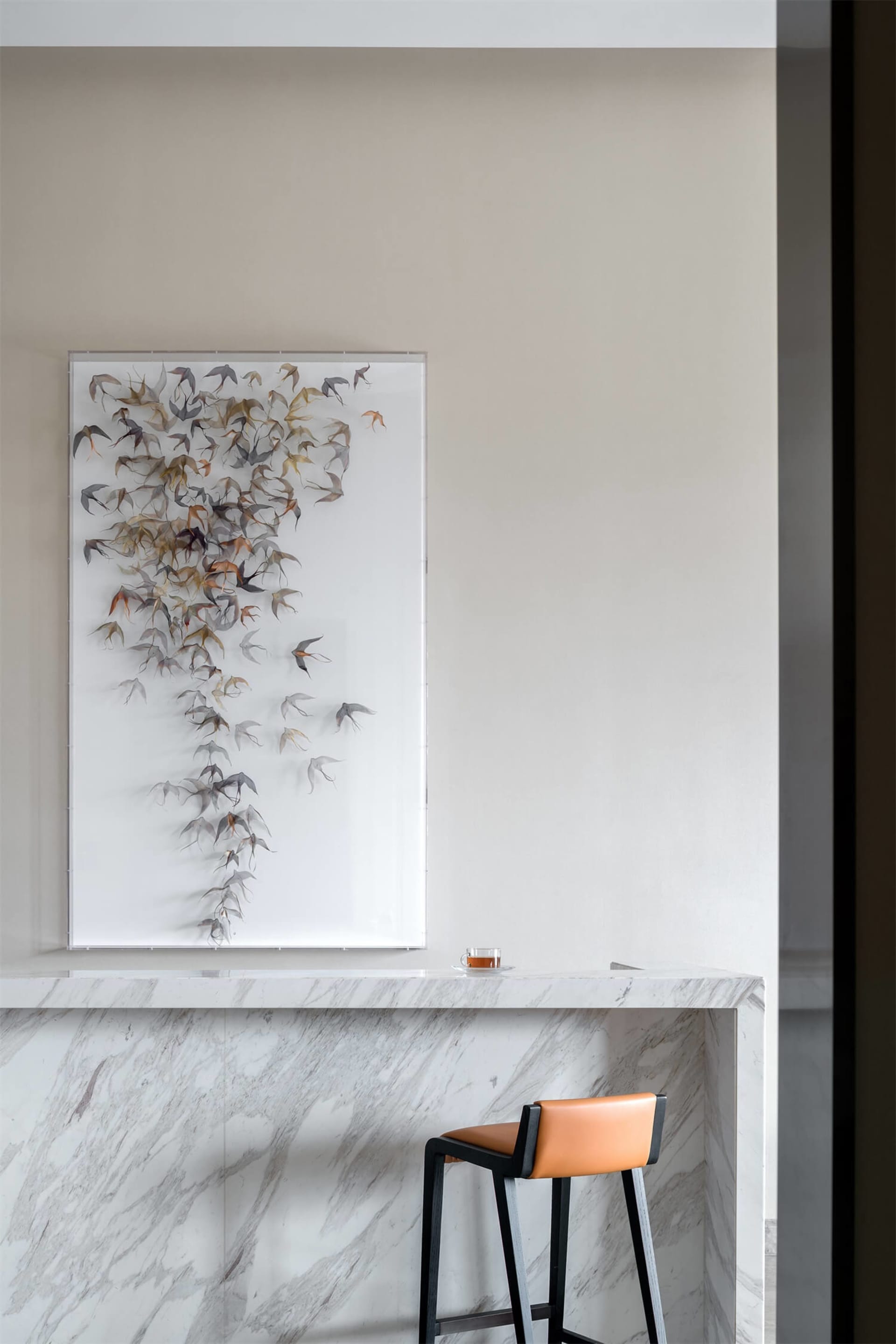 A modern interior design featuring marble materials, with a bird art sculpture and a bar counter.