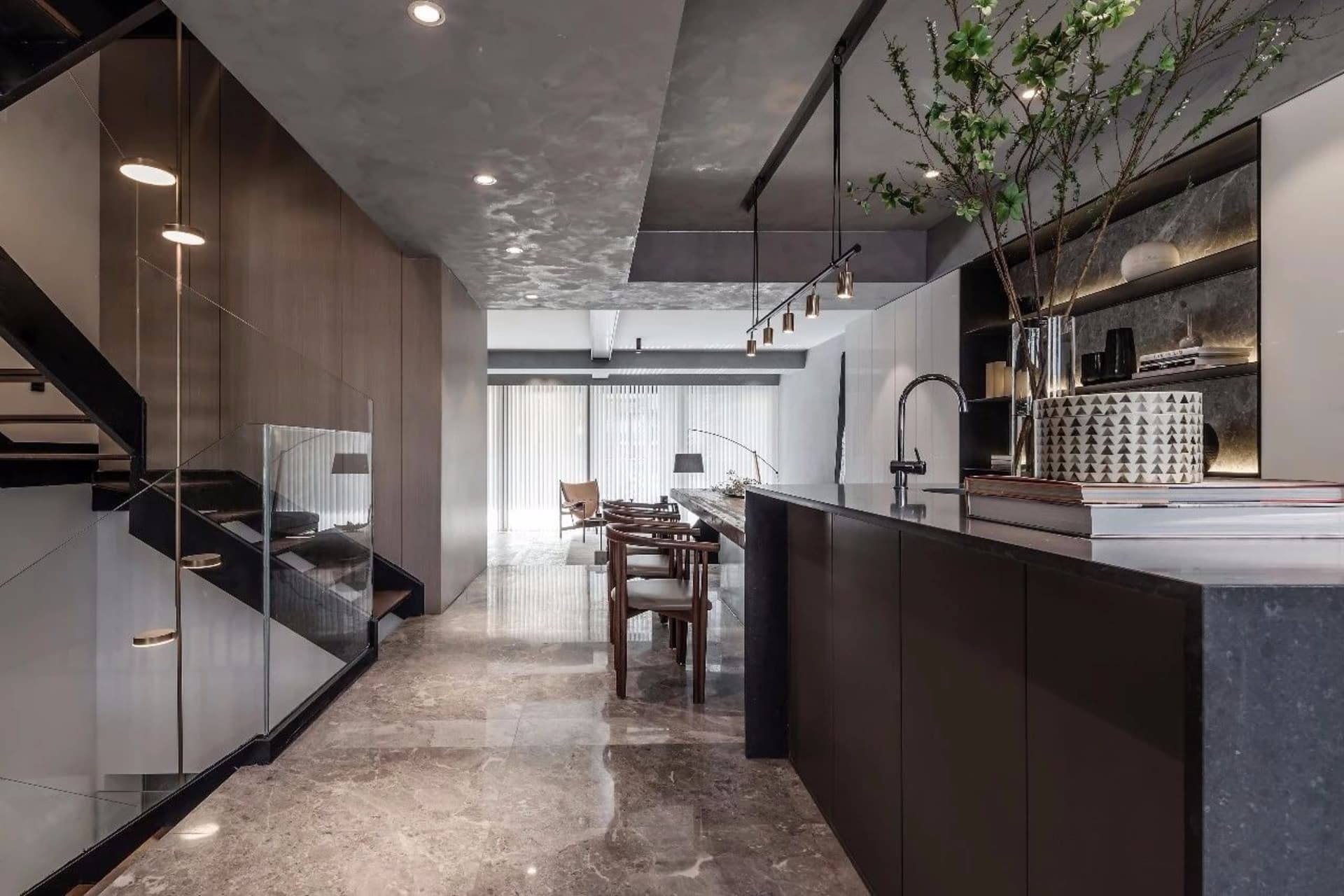 Modern kitchen with marble countertops and floor, featuring minimalist design elements and sleek, black accents.