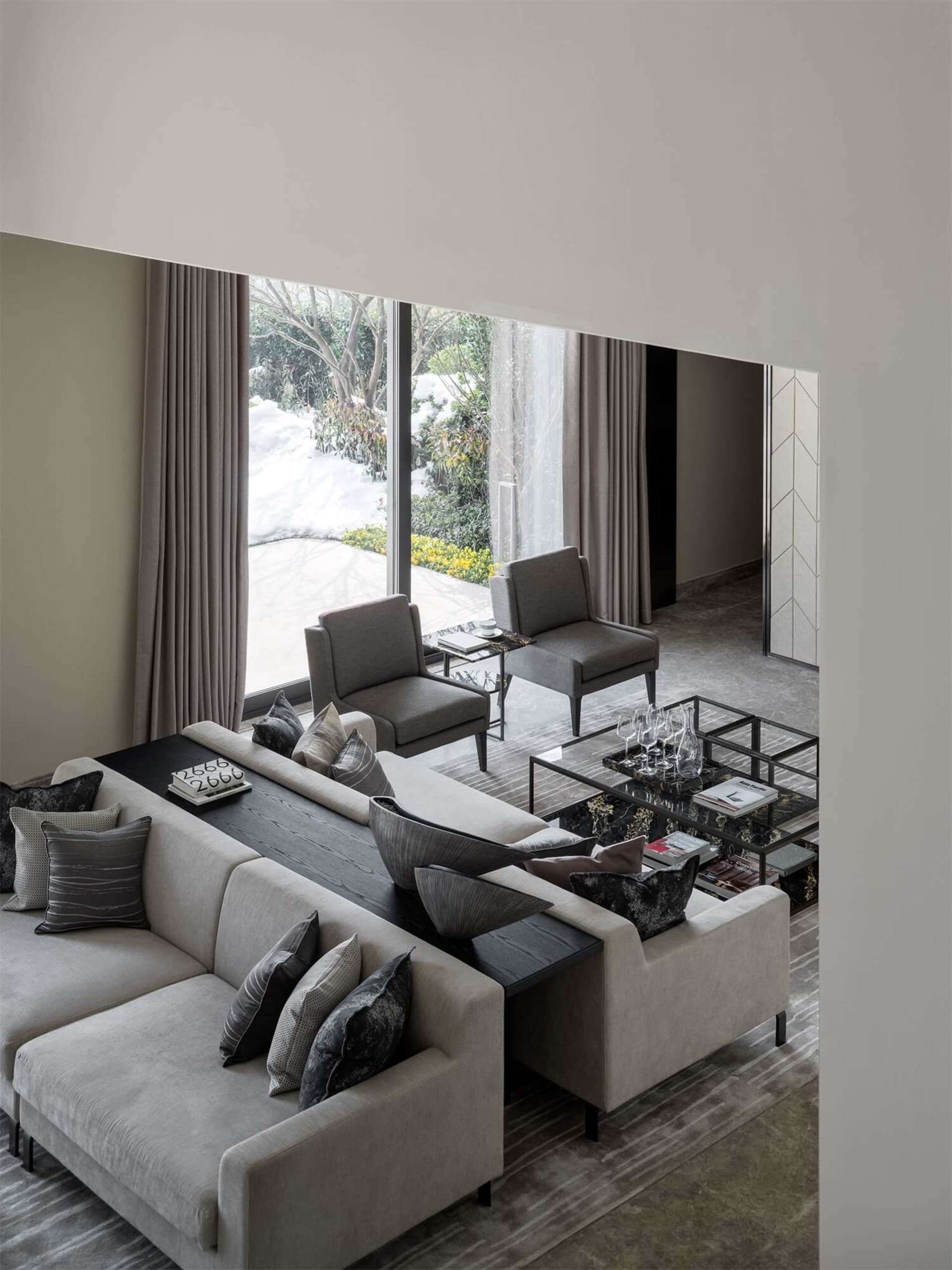 A modern grey living room with a comfortable sectional sofa adorned with dark grey cushions and decorative pillows, accompani