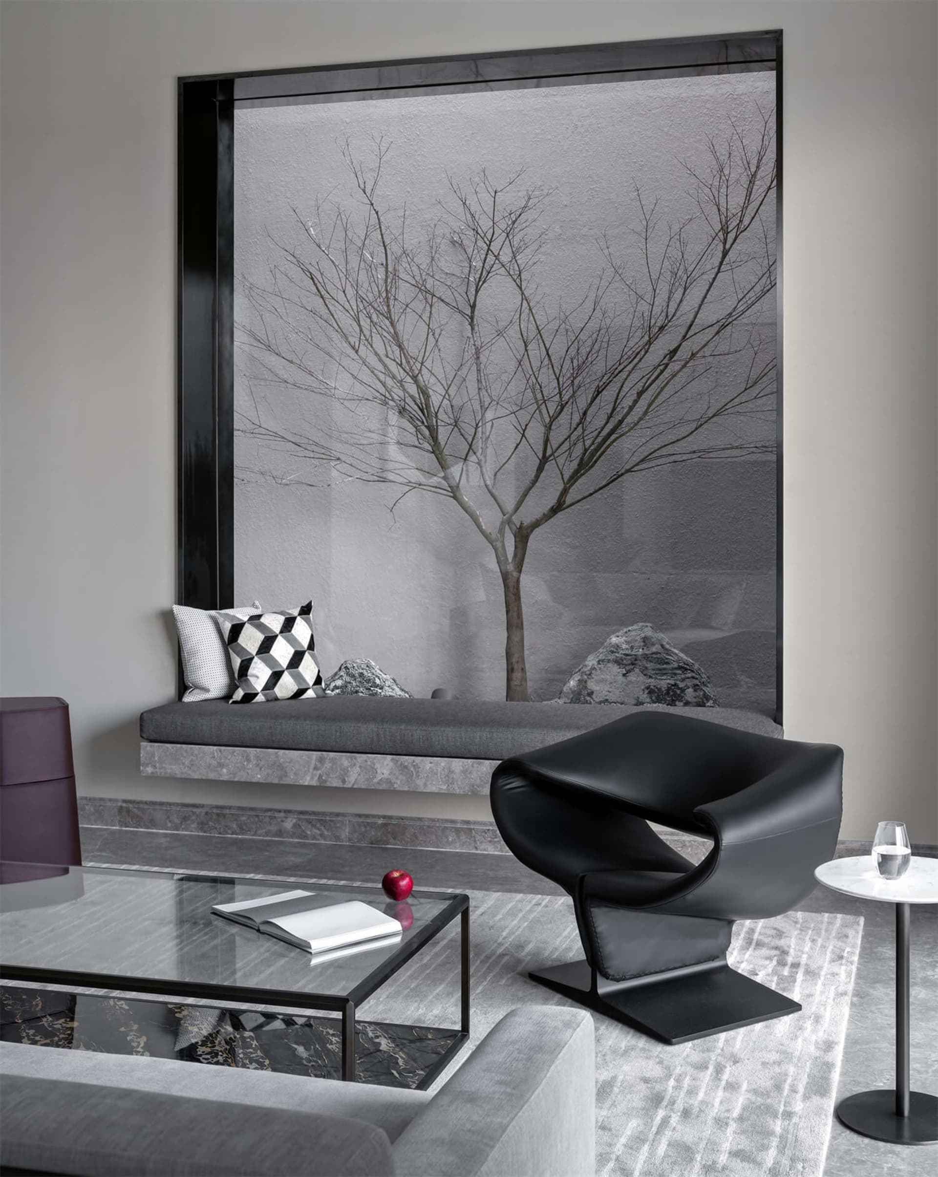 A modern living room featuring a glass window with a minimalist tree and rock garden