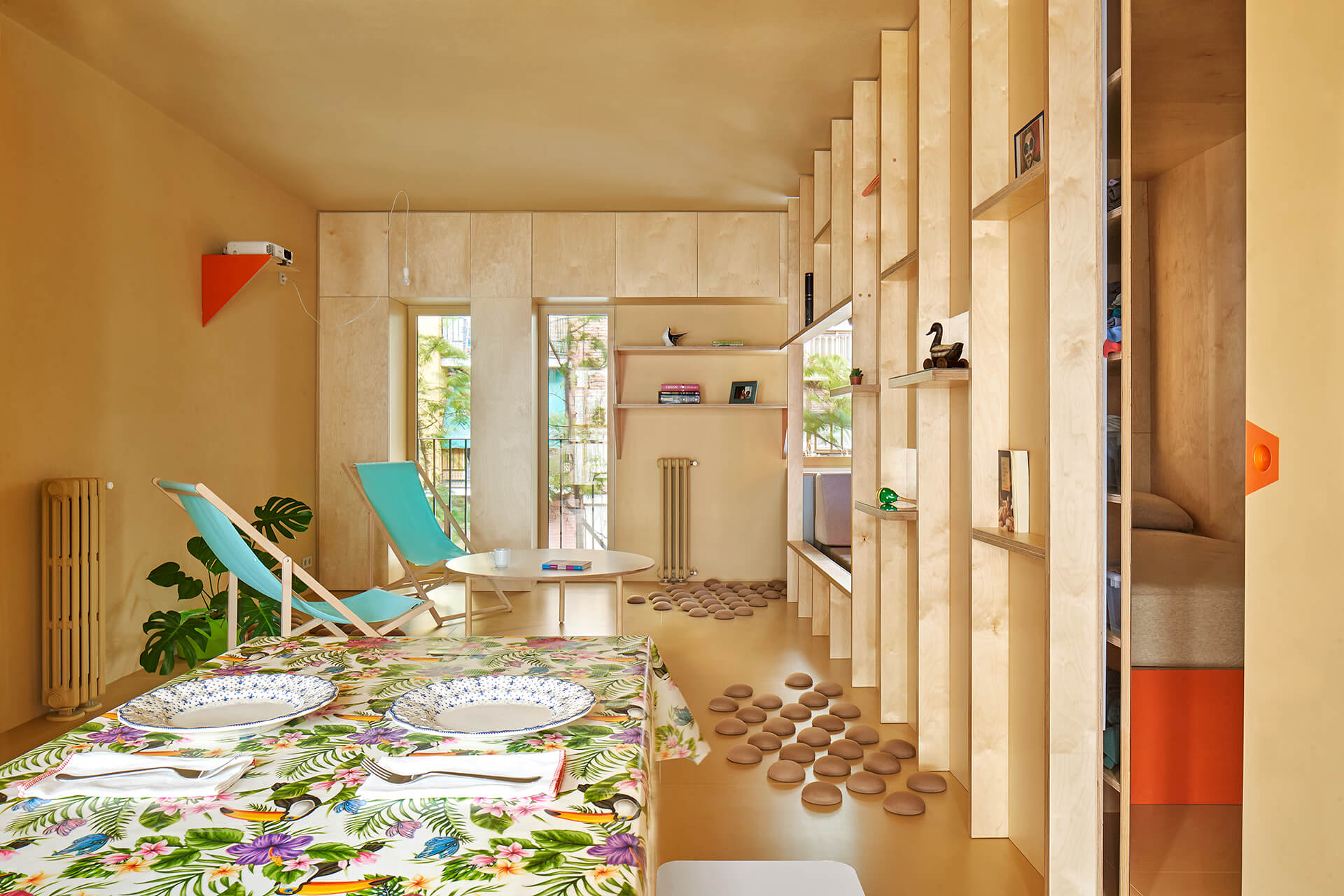 Modern small apartment with wooden plywood interior, featuring a dining table and chairs, a small table with a bird statue an