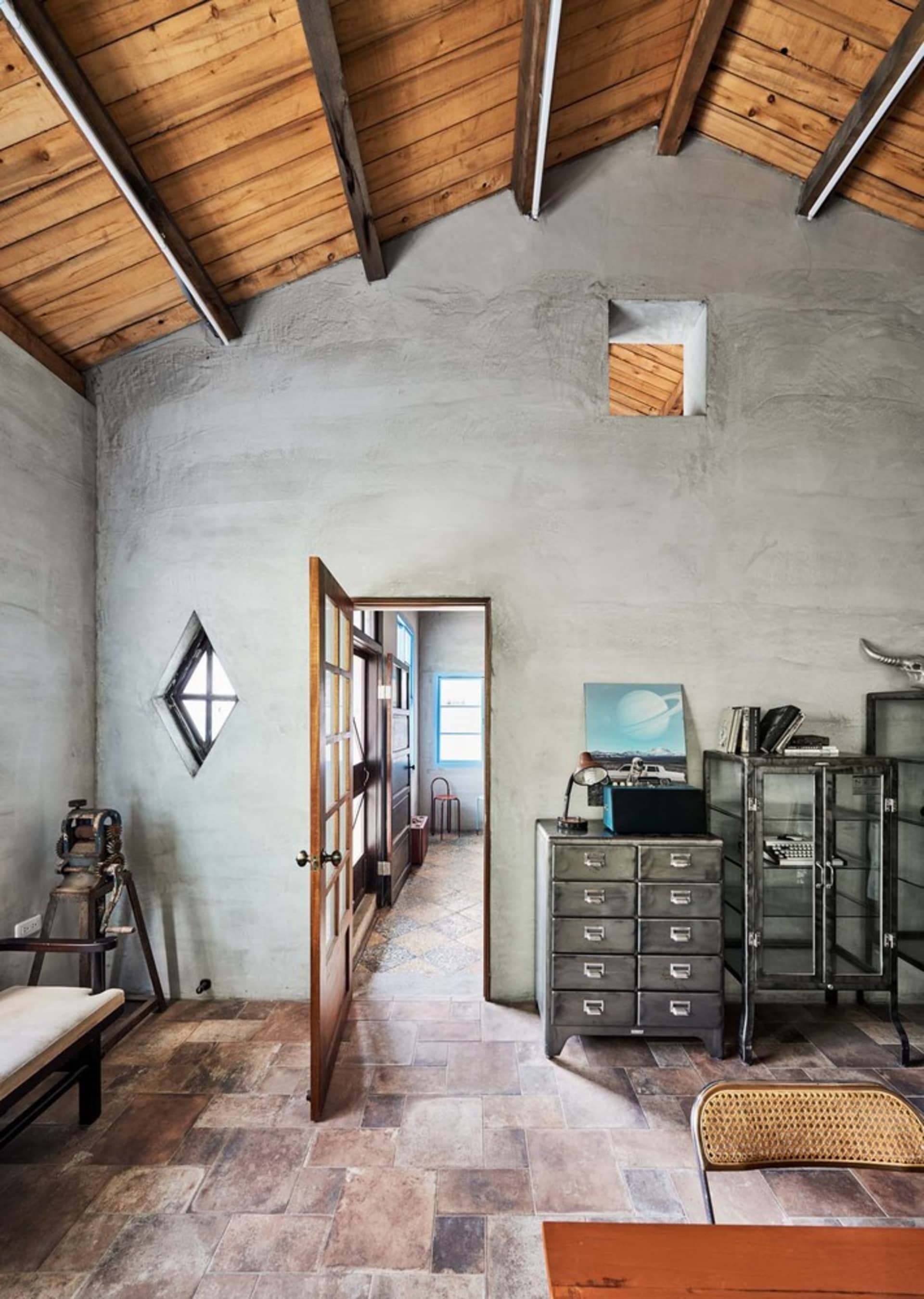Industrial office space featuring metal cabinets, wooden furniture, and plaster walls.