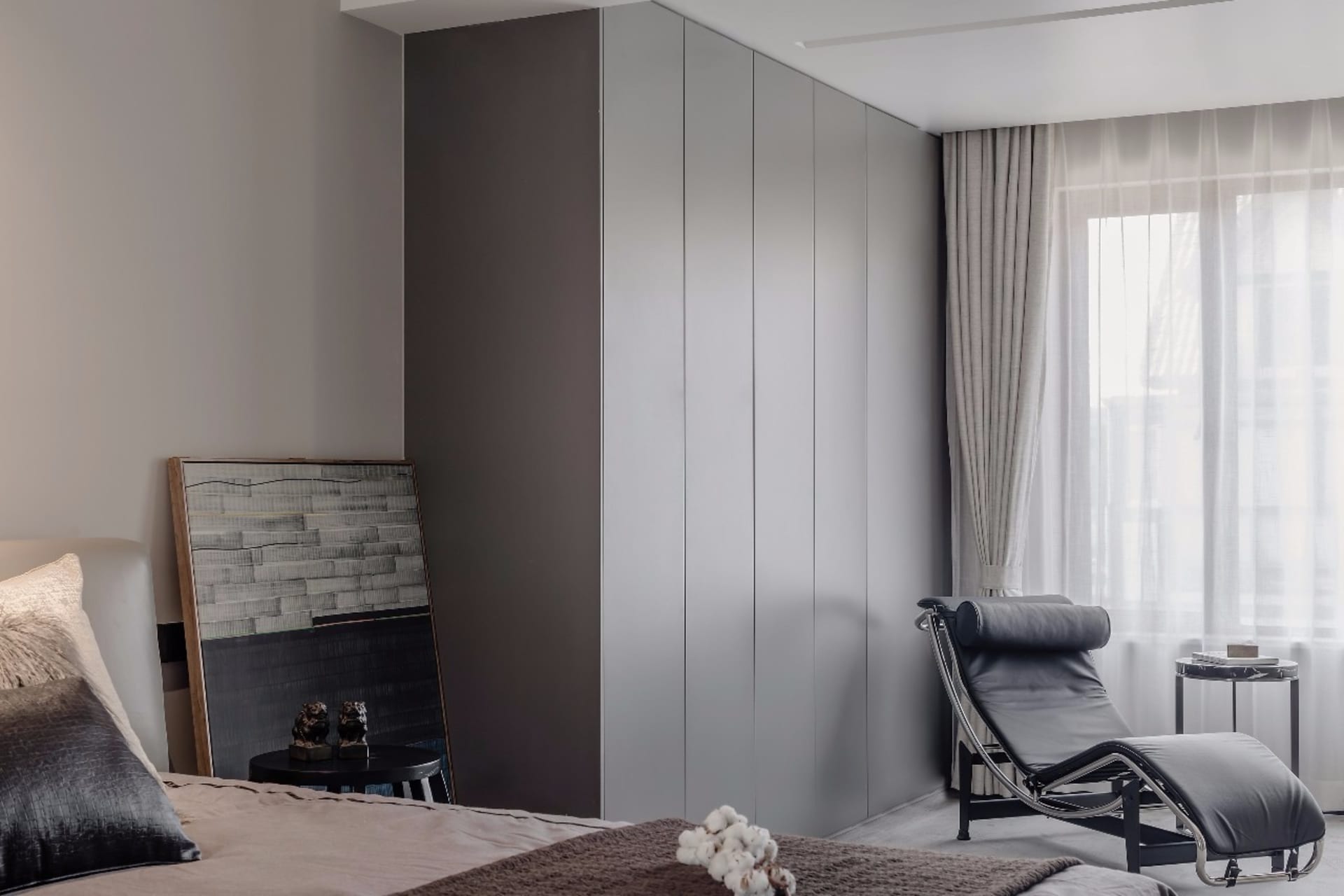 A modern minimalist bedroom featuring contemporary gray paneling and decorative cotton details.