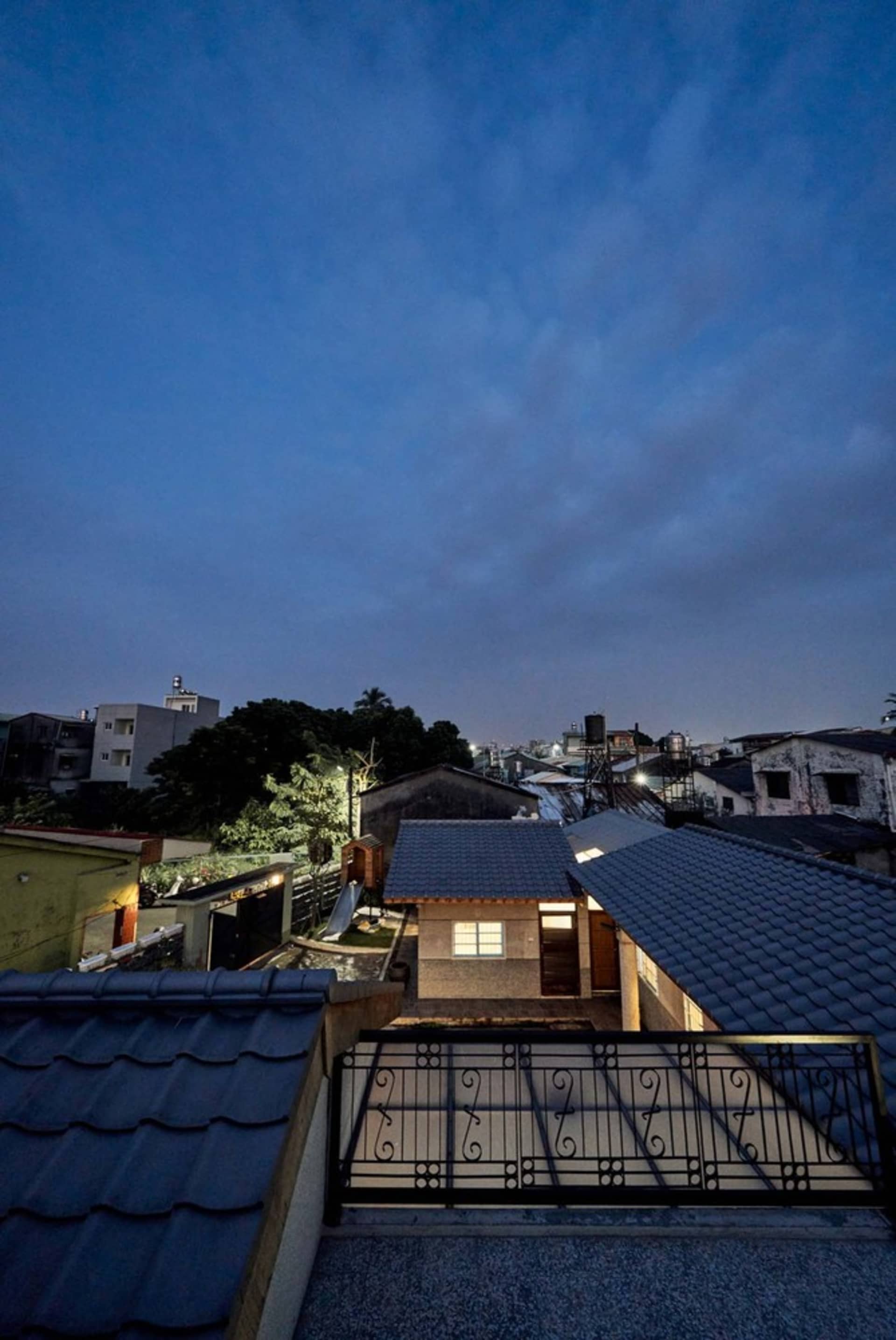 A residential exterior with a tiled roof and a metal fence.