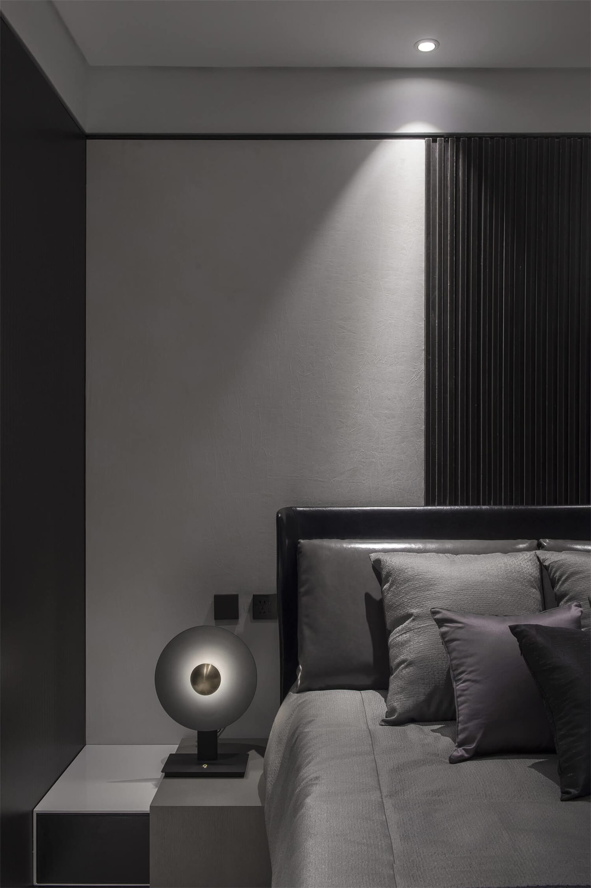 Bedroom with minimalist design featuring grey textured fabric bedding and wooden accents.