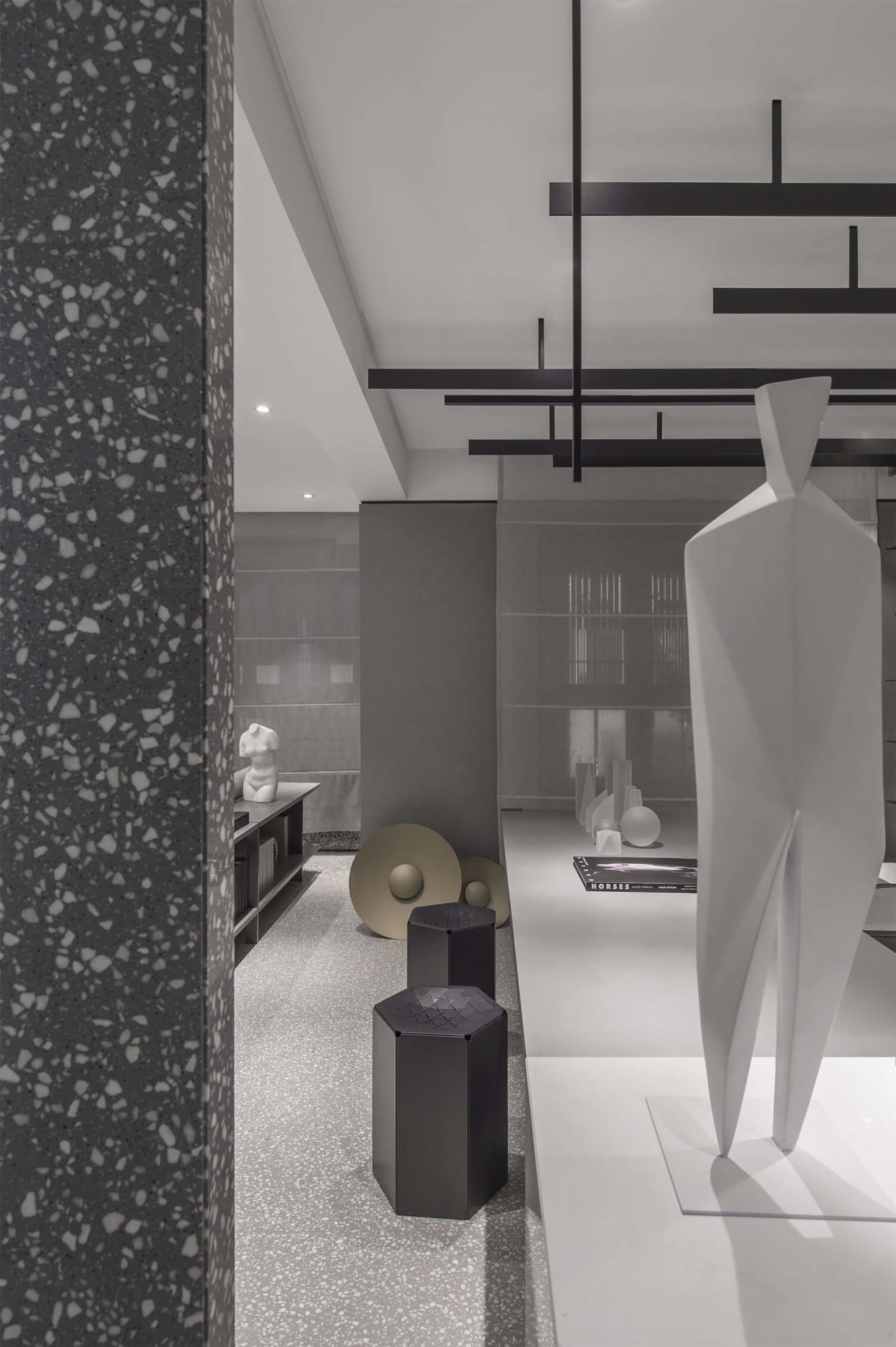 Modern interior featuring white and textured gray floor tiles with black accents and geometric shapes.