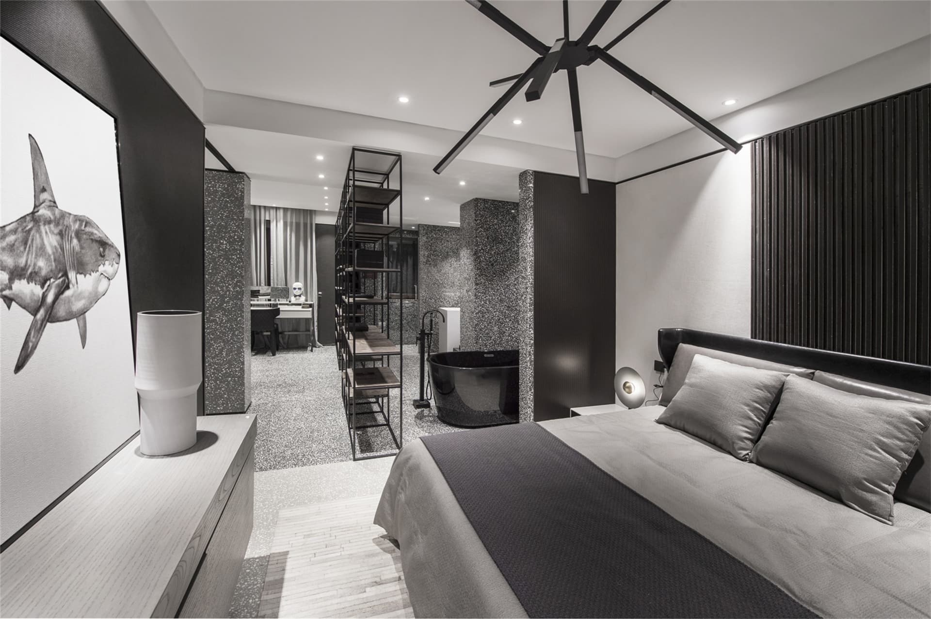 Contemporary bedroom with black, grey, and white palette, featuring a king-sized bed with a black headboard and grey linens, 