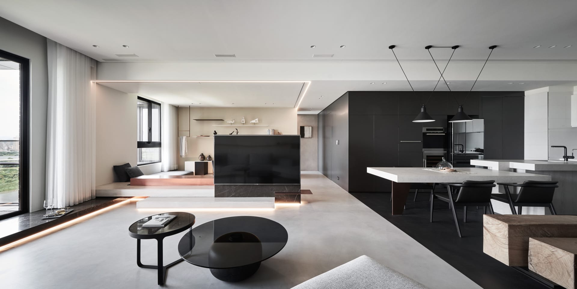 A modern living room with sleek, minimalist furniture and concrete flooring.