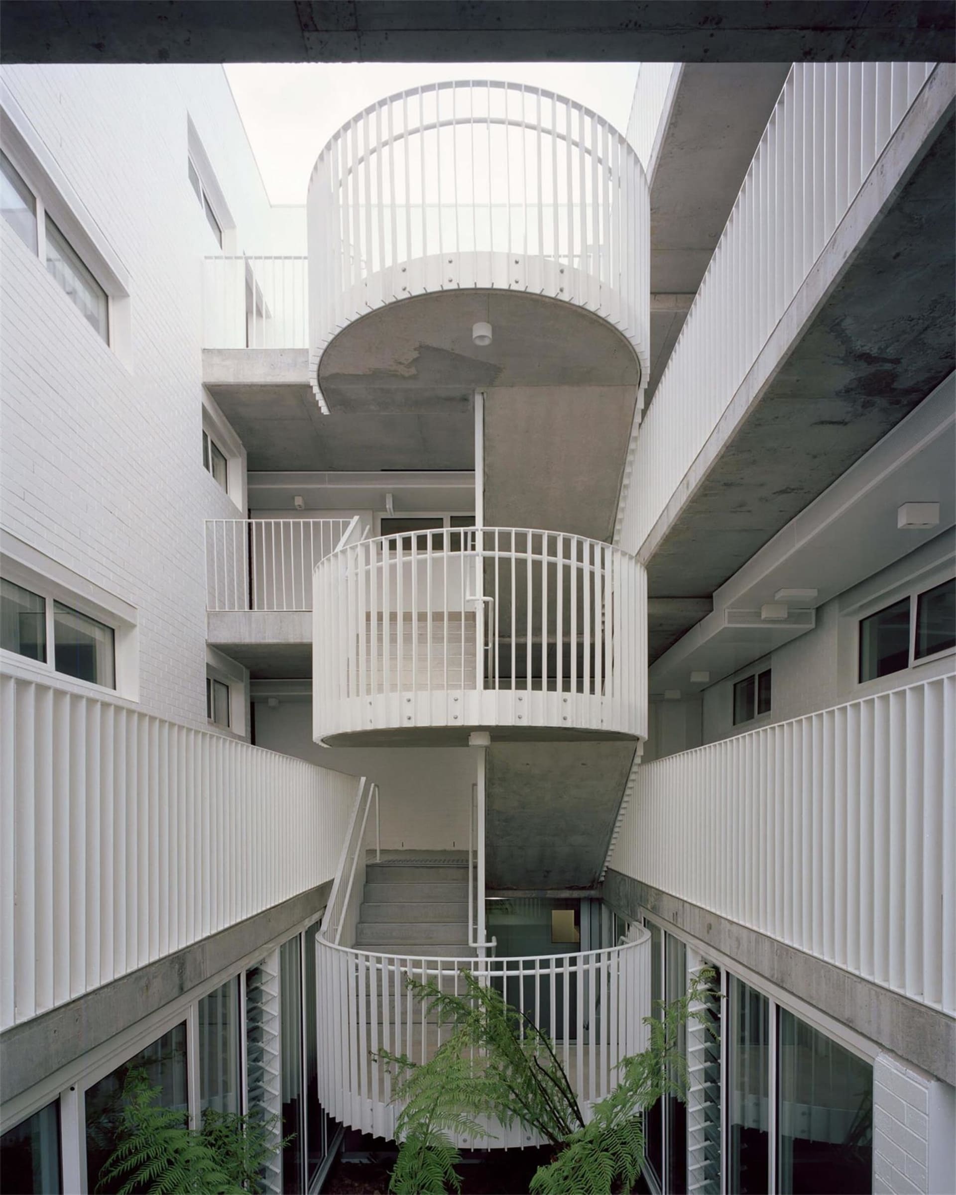 現代住宅建築,混凝土牆面搭配白色金屬欄杆與樓梯。