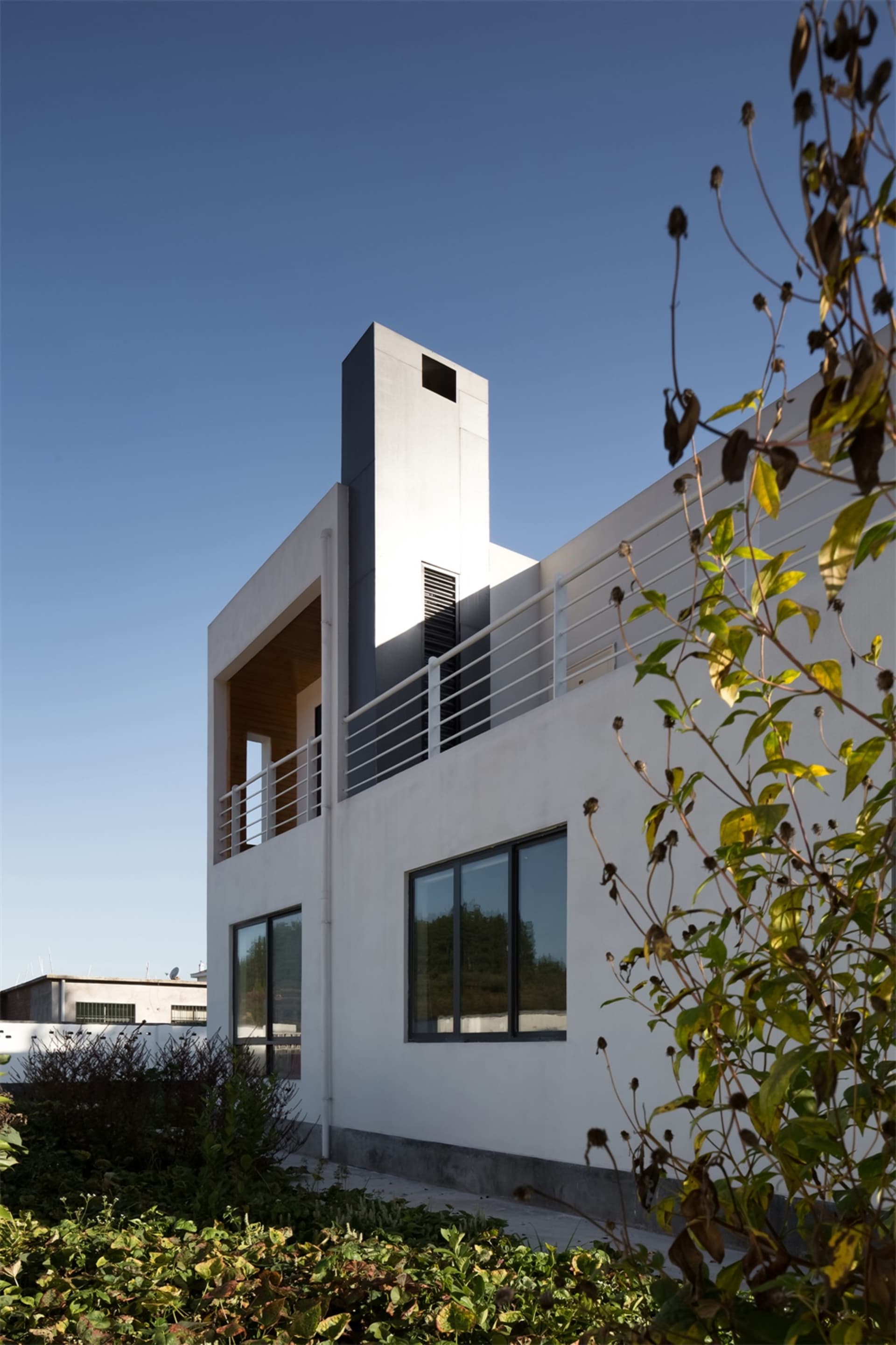 Modern design residential home with concrete facade, glass windows, and metal railings.