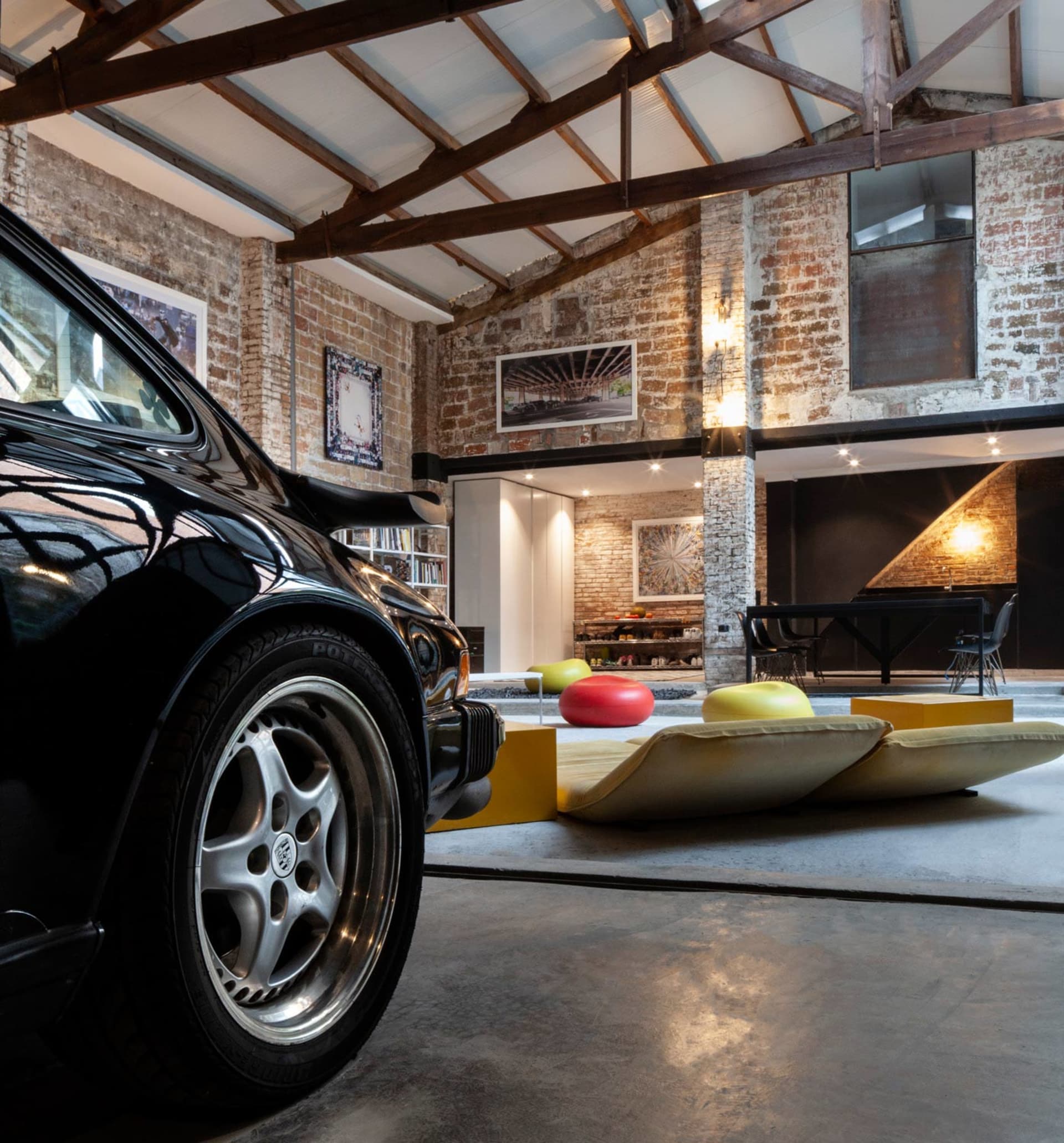 Industrial living room featuring exposed brick walls and concrete floors, with metal and wooden furniture.