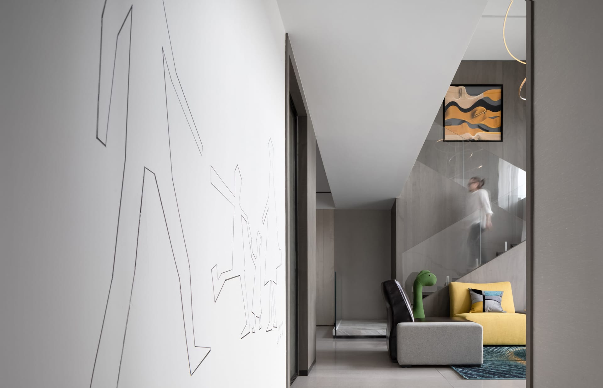 A modern living room with concrete flooring, a yellow sofa, and a white wall with abstract art.