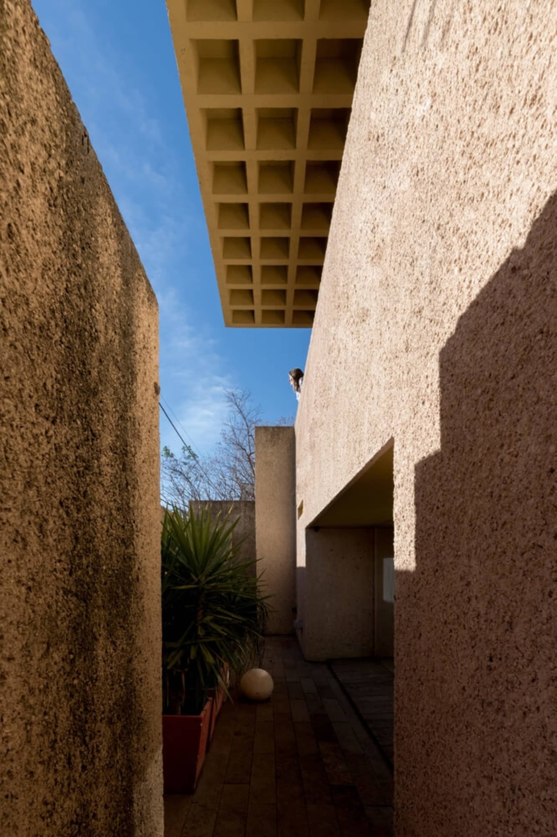 Modern architectural design featuring concrete walls and a geometric ceiling structure.