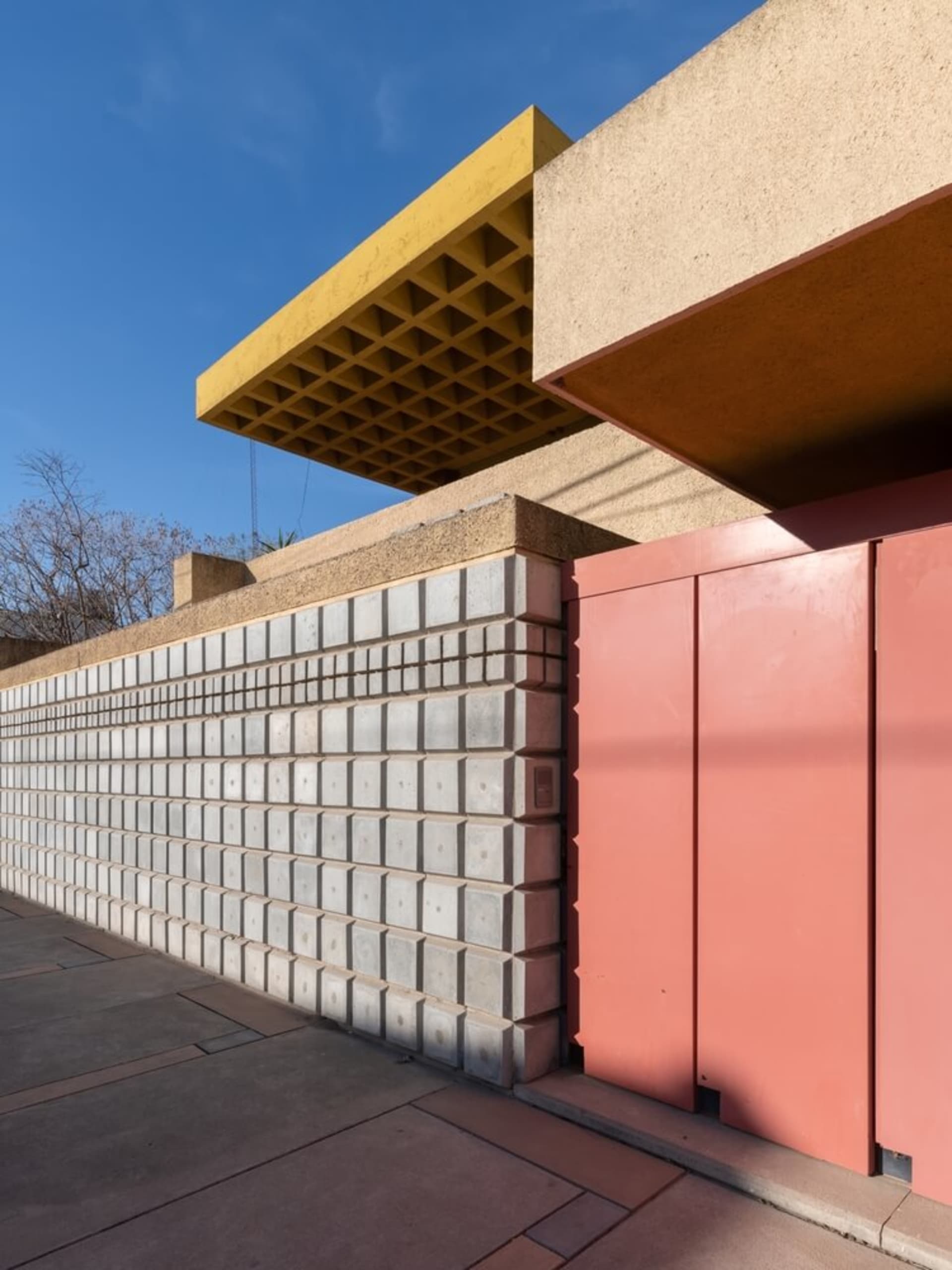 A modern building facade featuring a concrete wall and a red door.