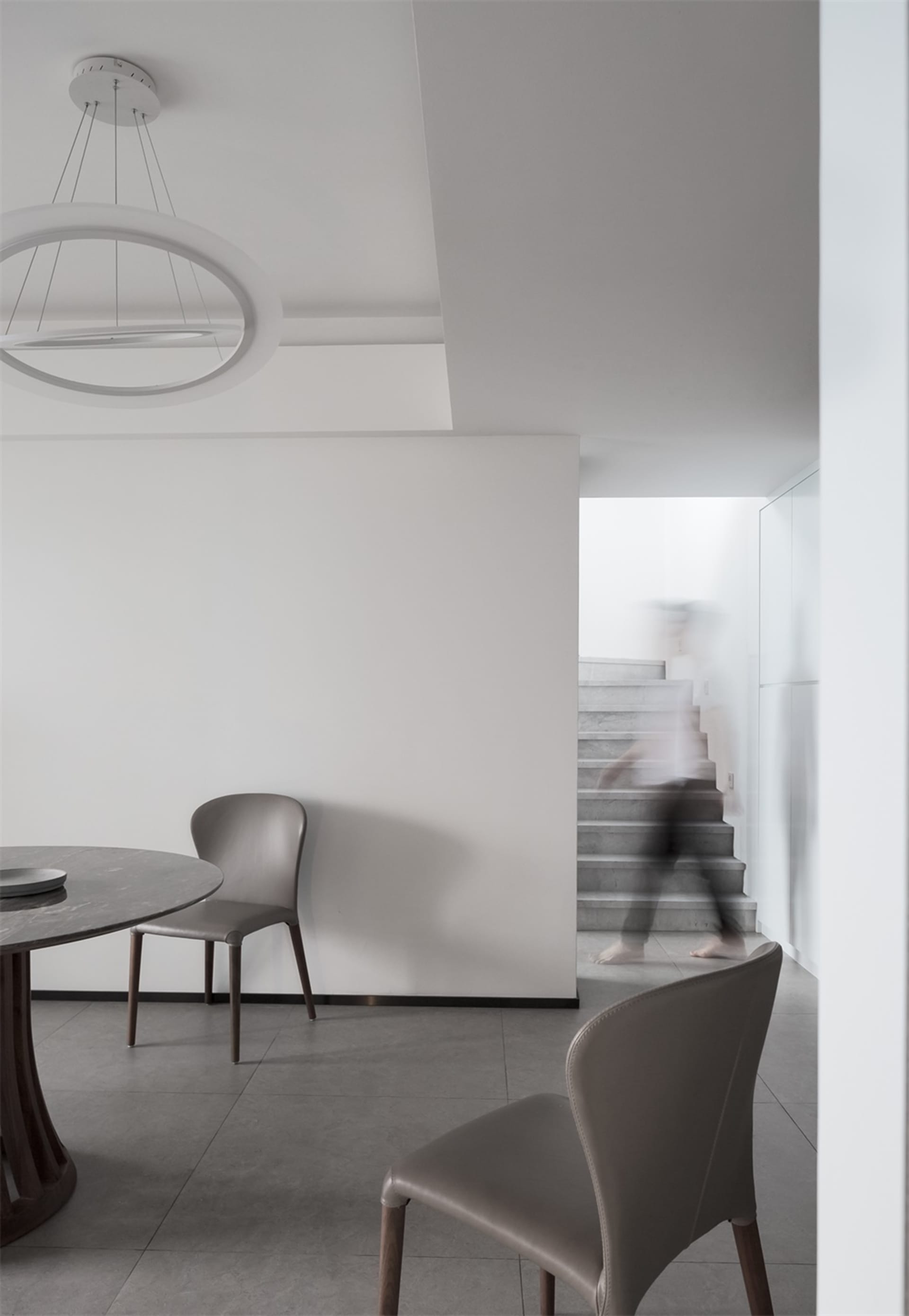 Modern minimalist dining room with concrete elements and a round marble table.