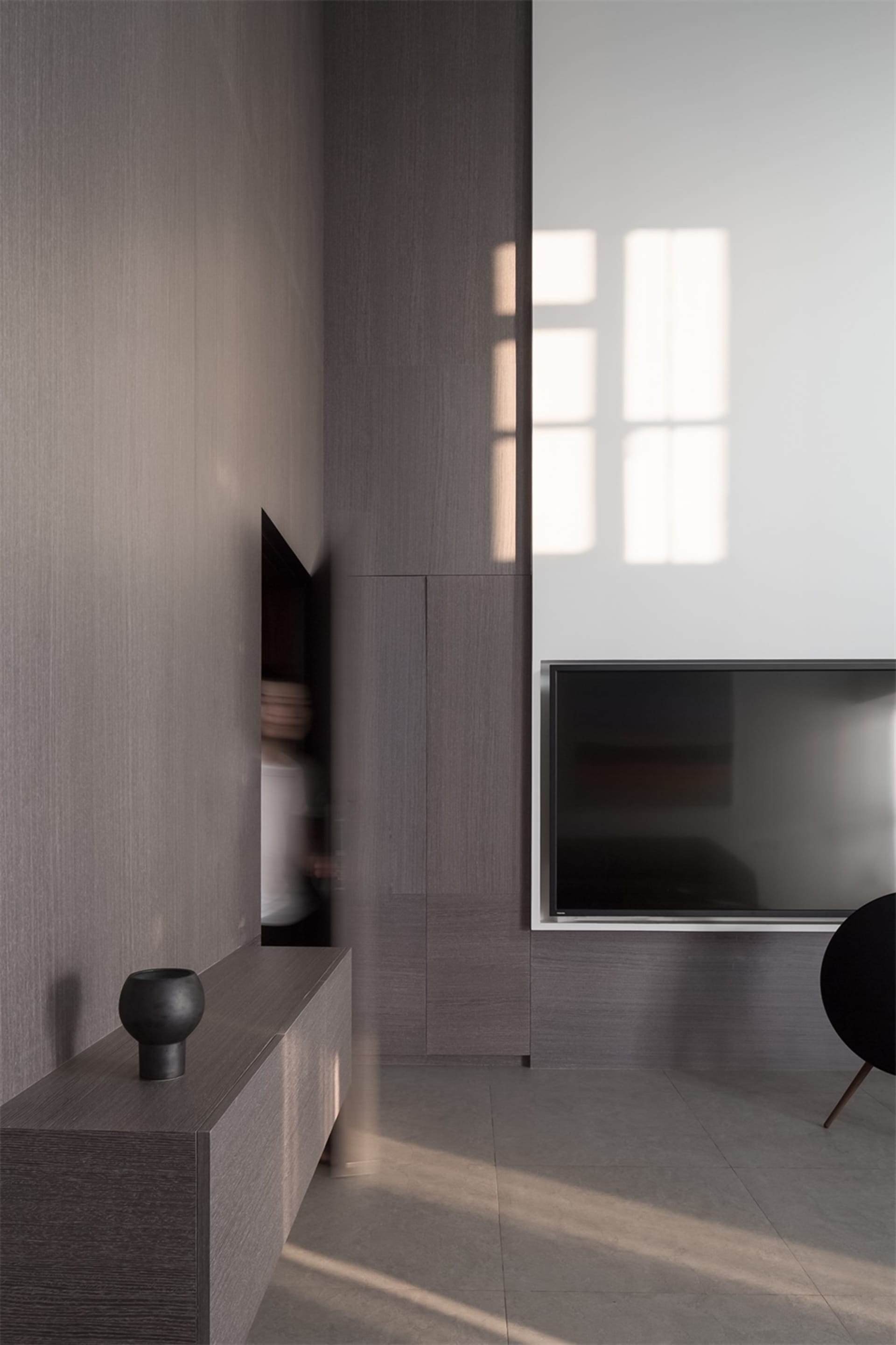 Modern living room with dark wood finishes, featuring a sleek flat-screen TV and minimalist interior design.