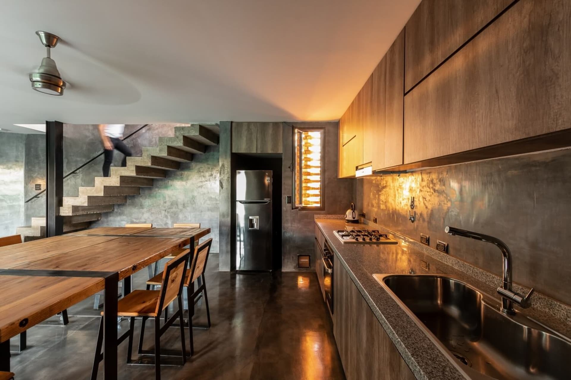 A modern residential kitchen featuring steel appliances, wooden accents, and concrete elements.