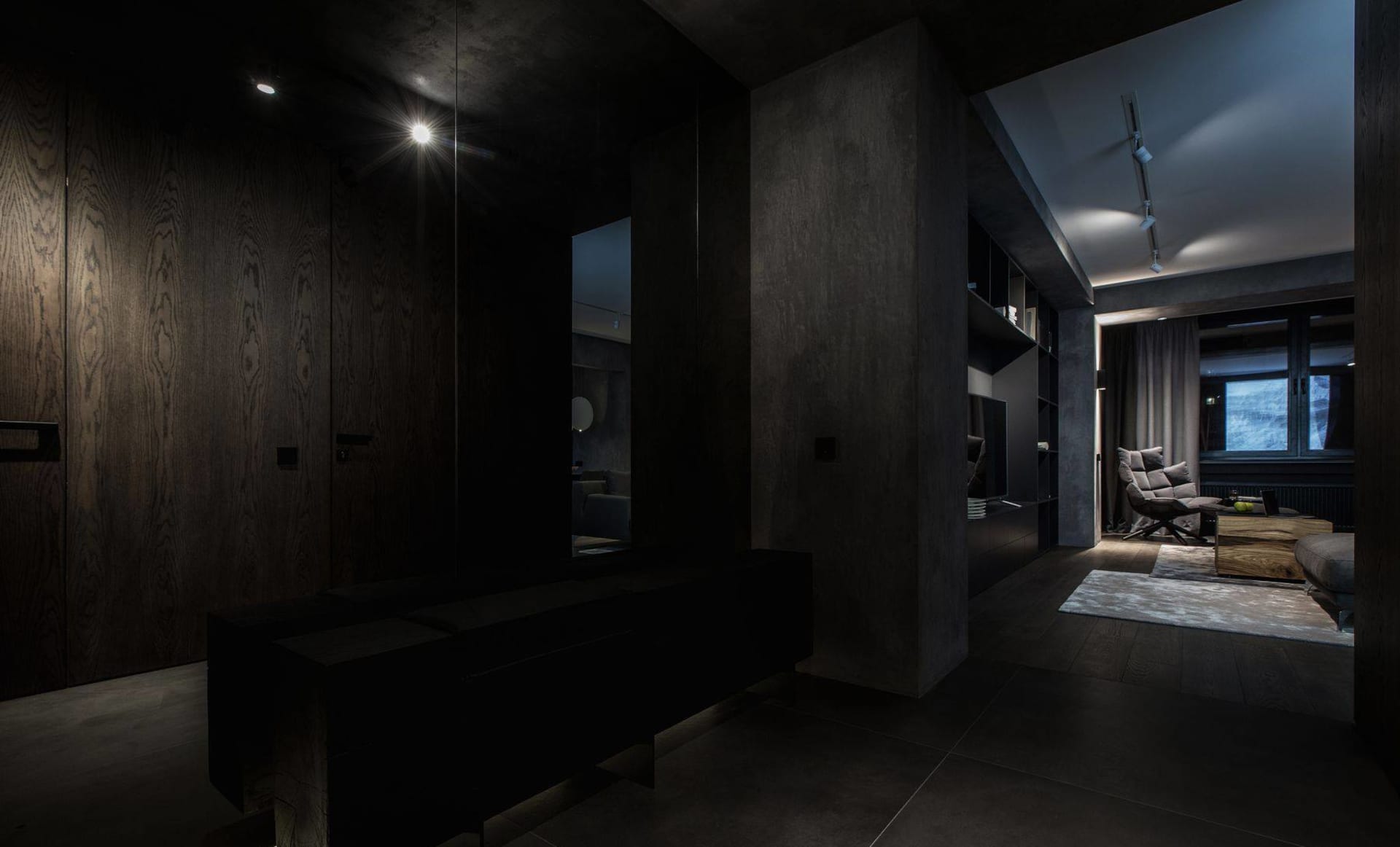 A modern living room with dark concrete walls and minimalist furniture.
