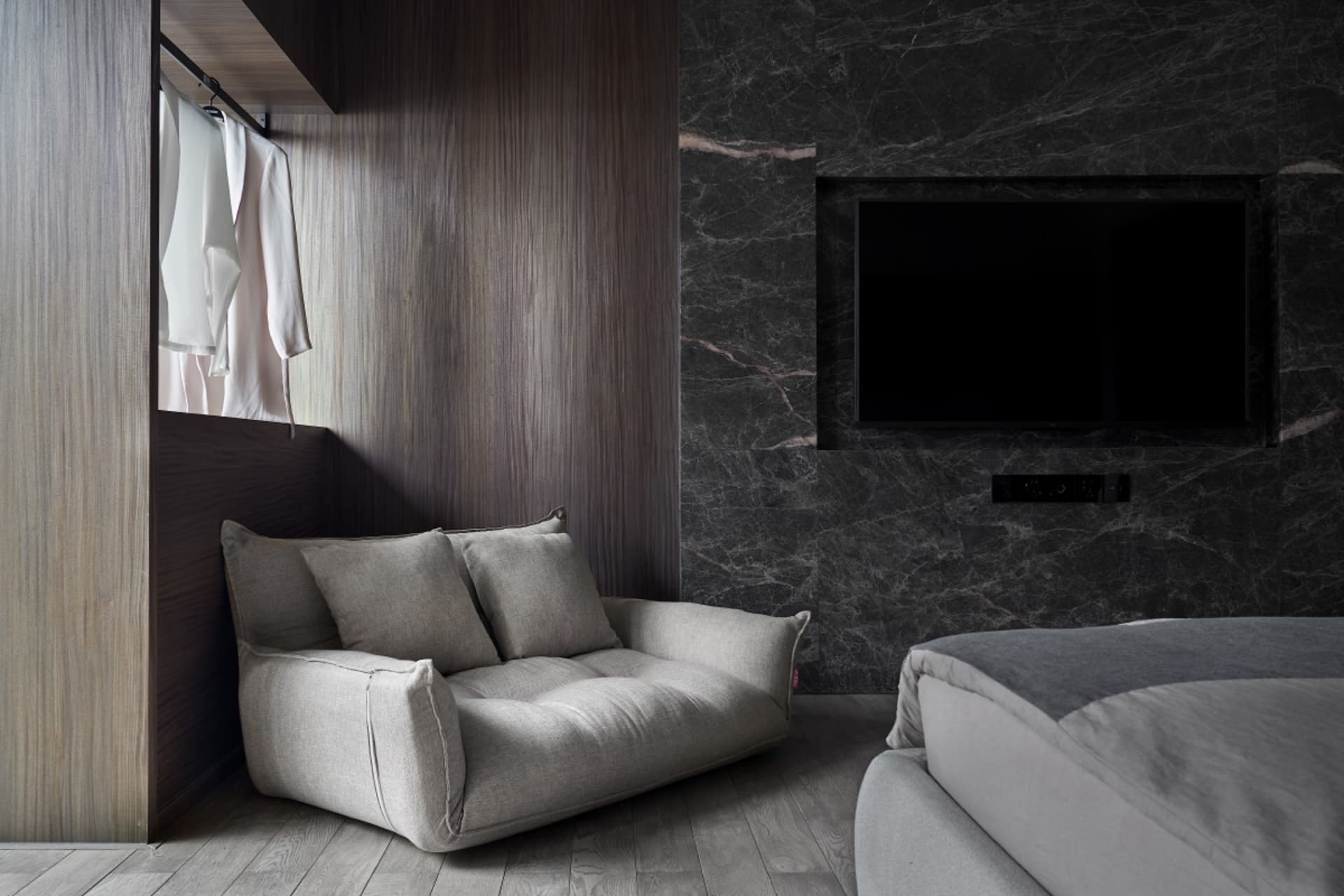 A modern bedroom featuring marble walls and wood accents.
