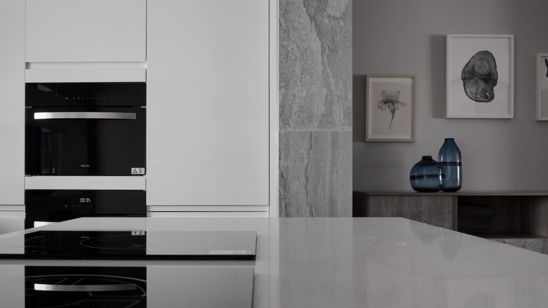 Modern kitchen with marble countertops and sleek, white cabinets.