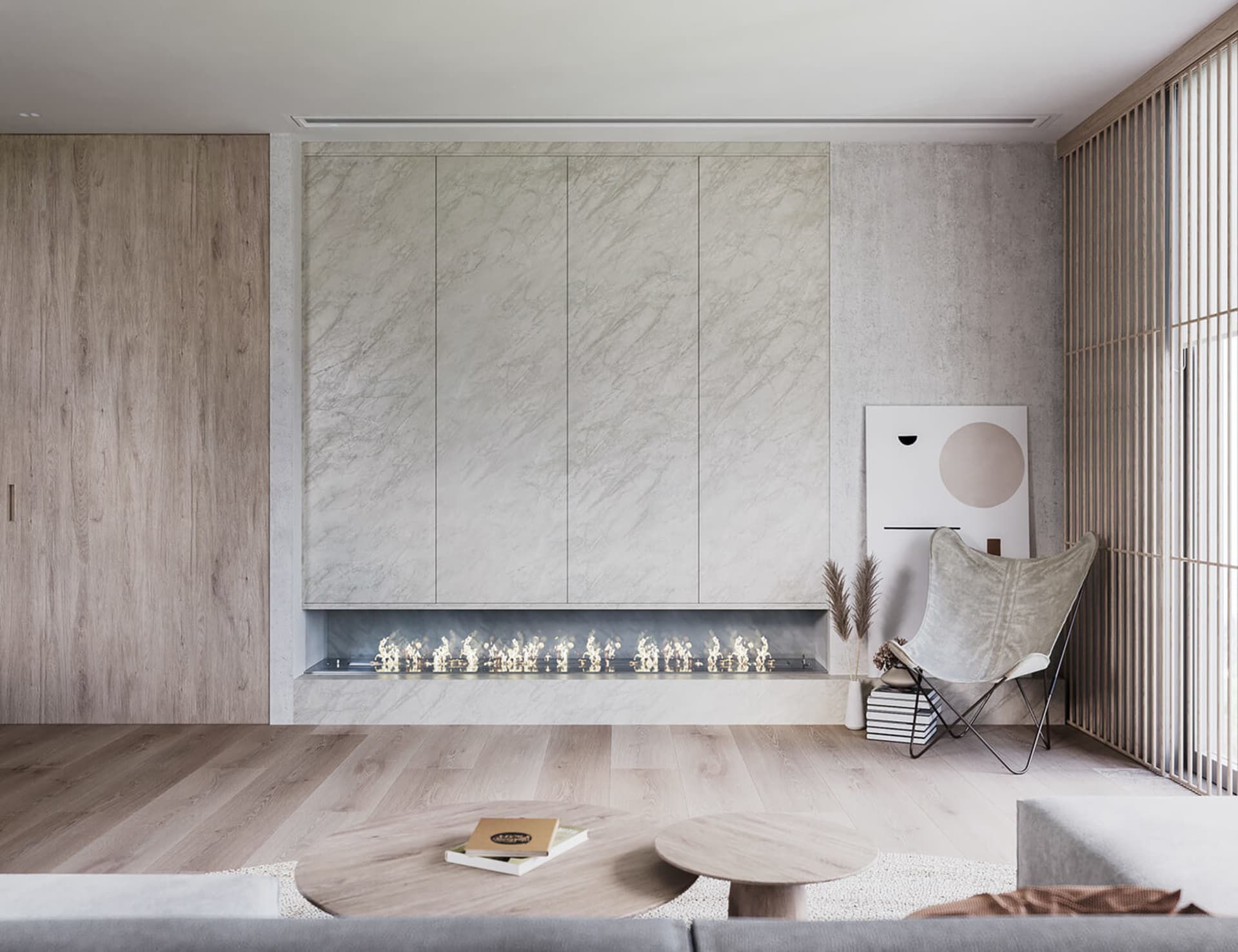 A modern living room featuring a marble wall with a linear fireplace, a wooden floor, and a butterfly chair with books and dr