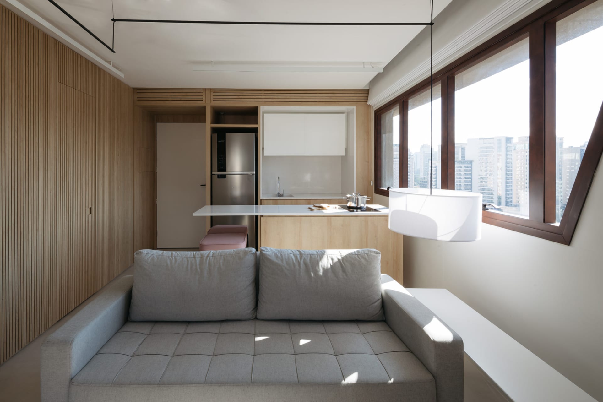 A minimalist residential interior with light-colored wood, white accents, and stainless steel kitchen appliances.