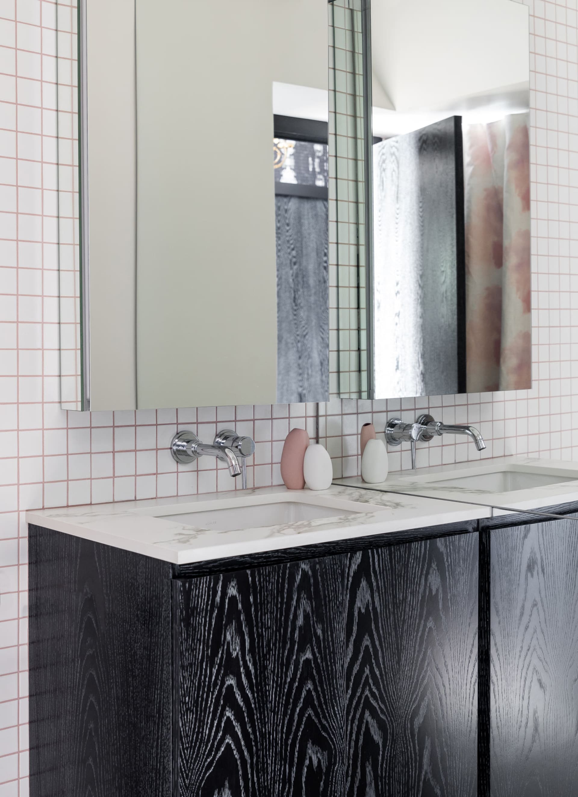 Modern bathroom with white and black marble tiles, black cabinets, and chrome faucets.