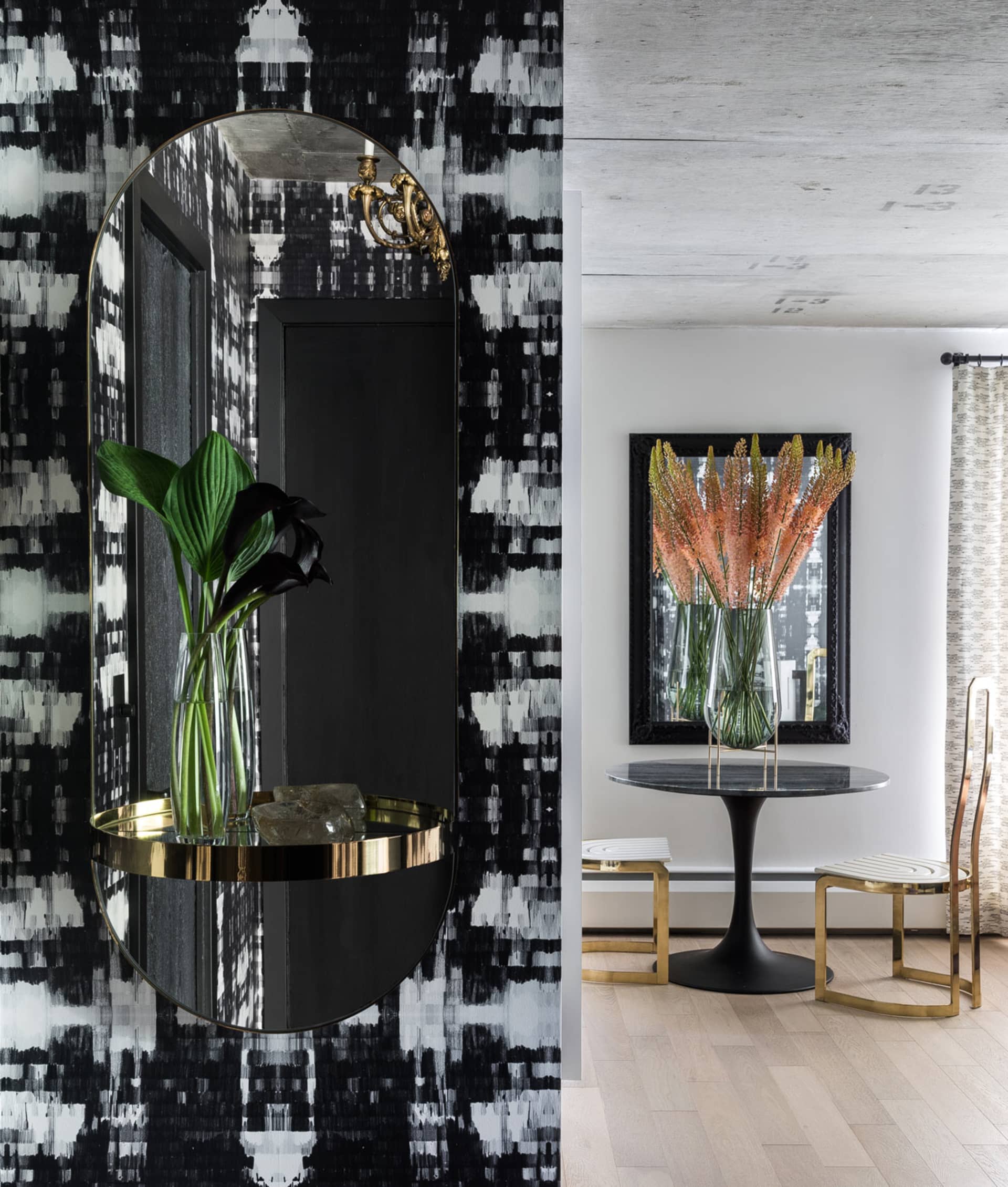 A modern entry way featuring glass, metallic accents, and botanical decor.