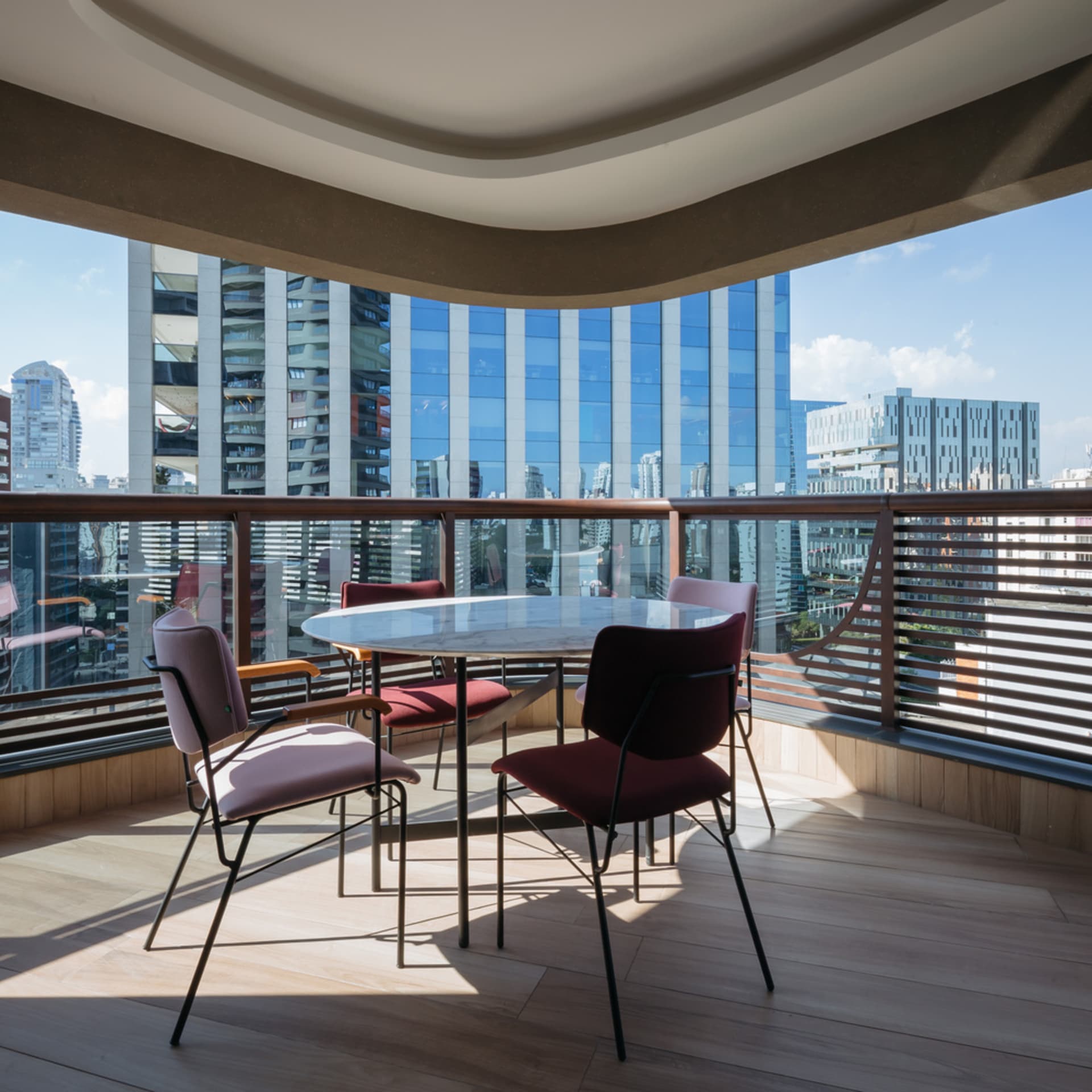 A modern interior design featuring a curved balcony with a view of high-rise buildings.