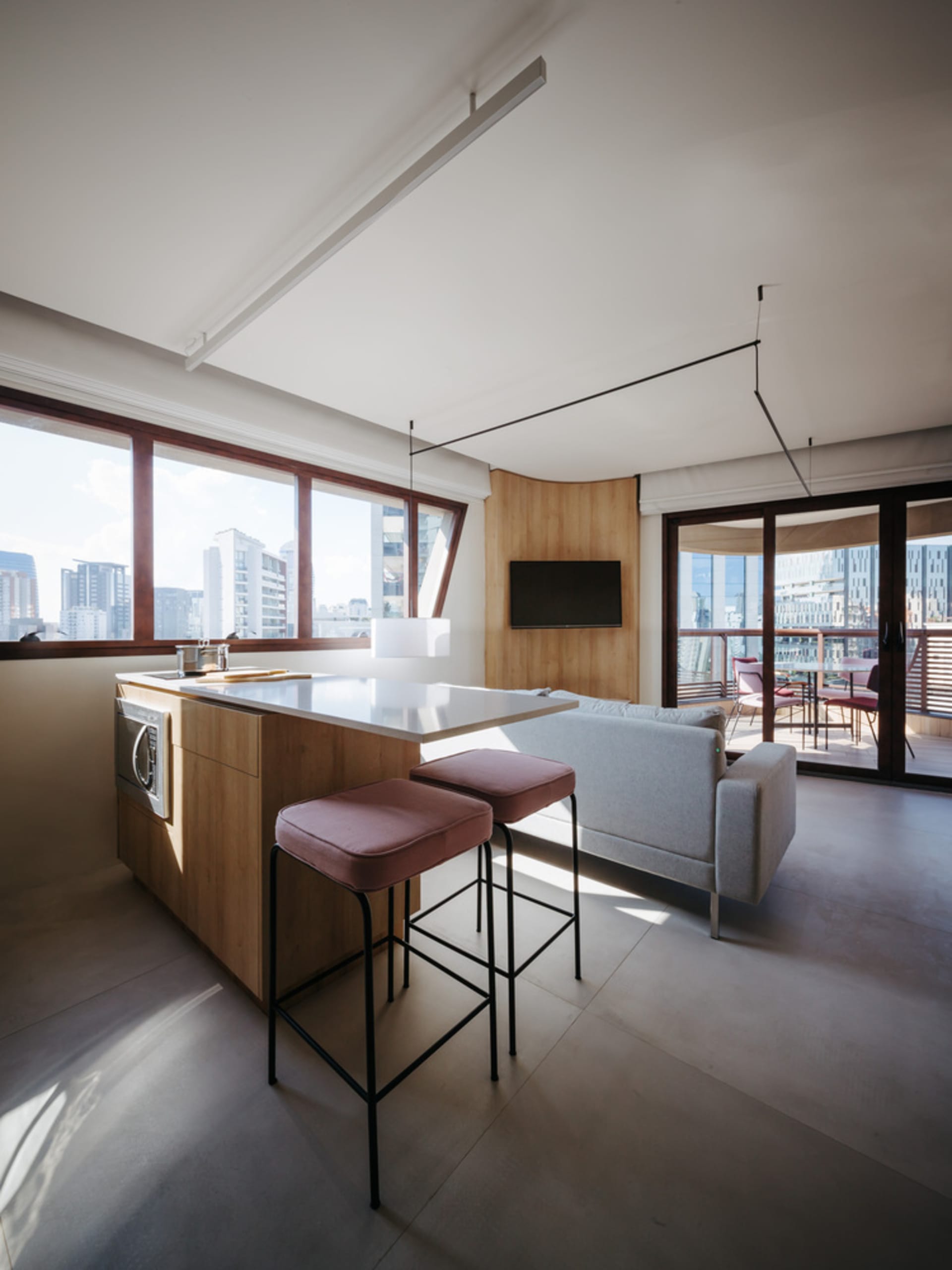 A modern kitchen with wooden cabinets, a white countertop, and a view of the city.