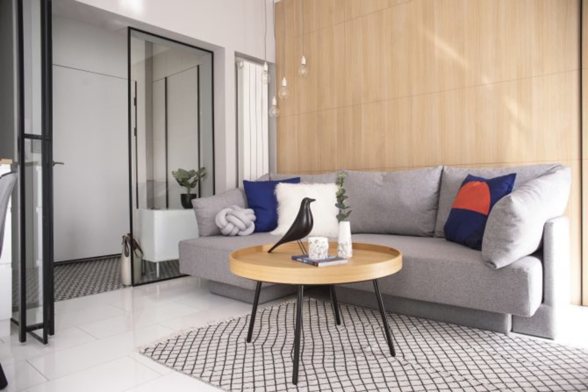 Modern living room featuring a large couch adorned with patterned cushions, surrounded by a wooden coffee table and patterned