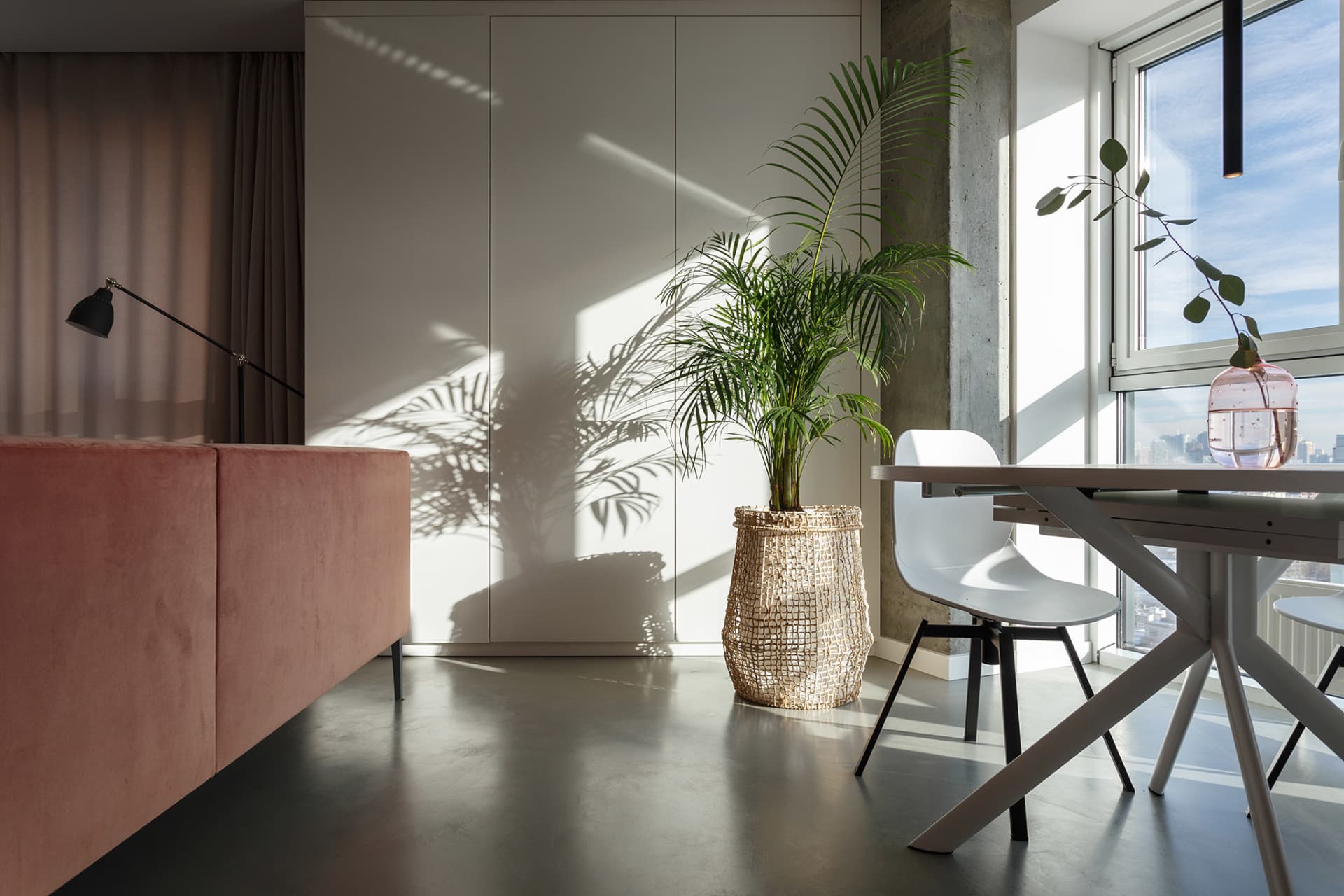 A spacious modern living room features concrete furniture and minimalist decor, creating a sleek and contemporary space.