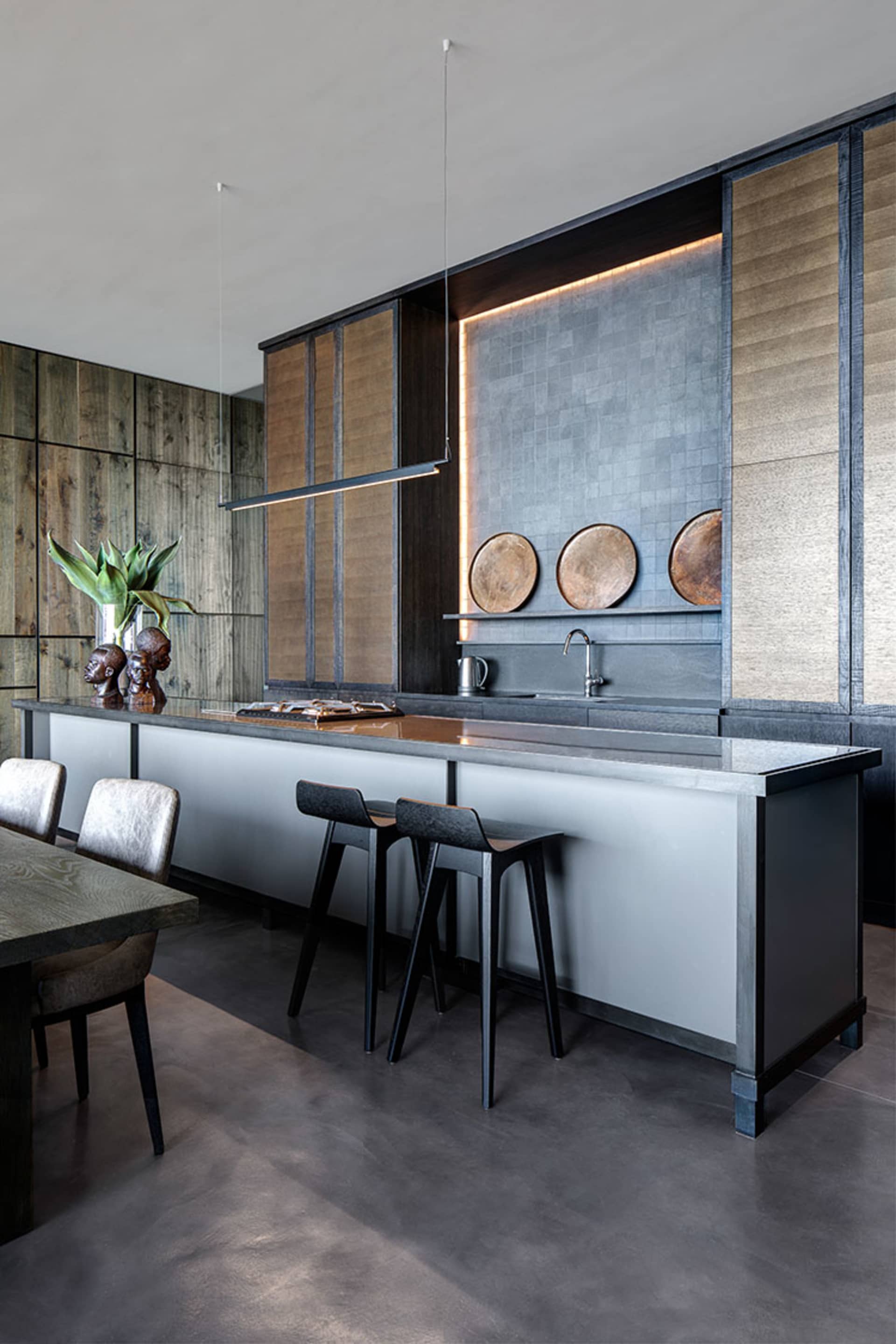 A modern kitchen featuring a kitchen island with a modern design and white and black countertop, surrounded by wooden cabinet
