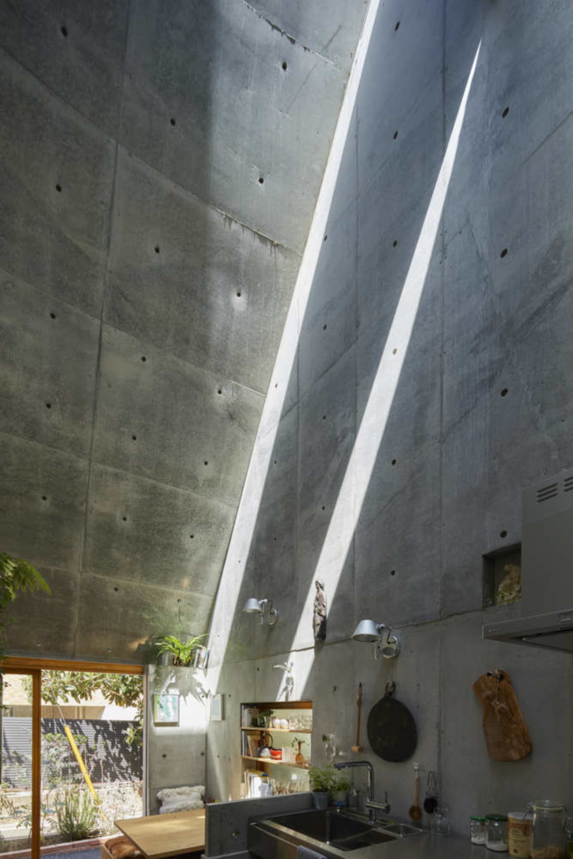 Concrete kitchen interior with modern design elements, featuring a high ceiling and natural light.