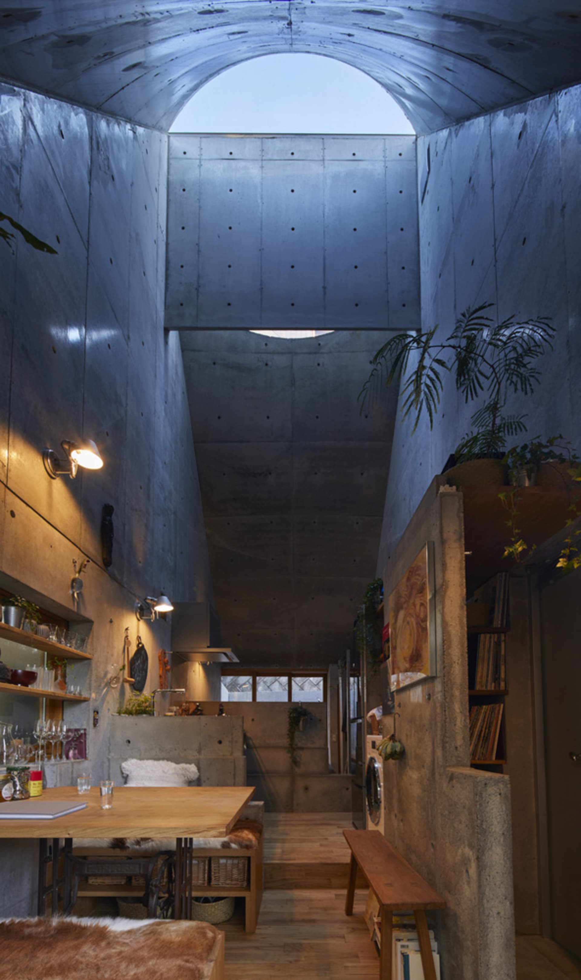 A modern, industrial residential interior with exposed concrete walls and a high, open ceiling, featuring a cozy living area 