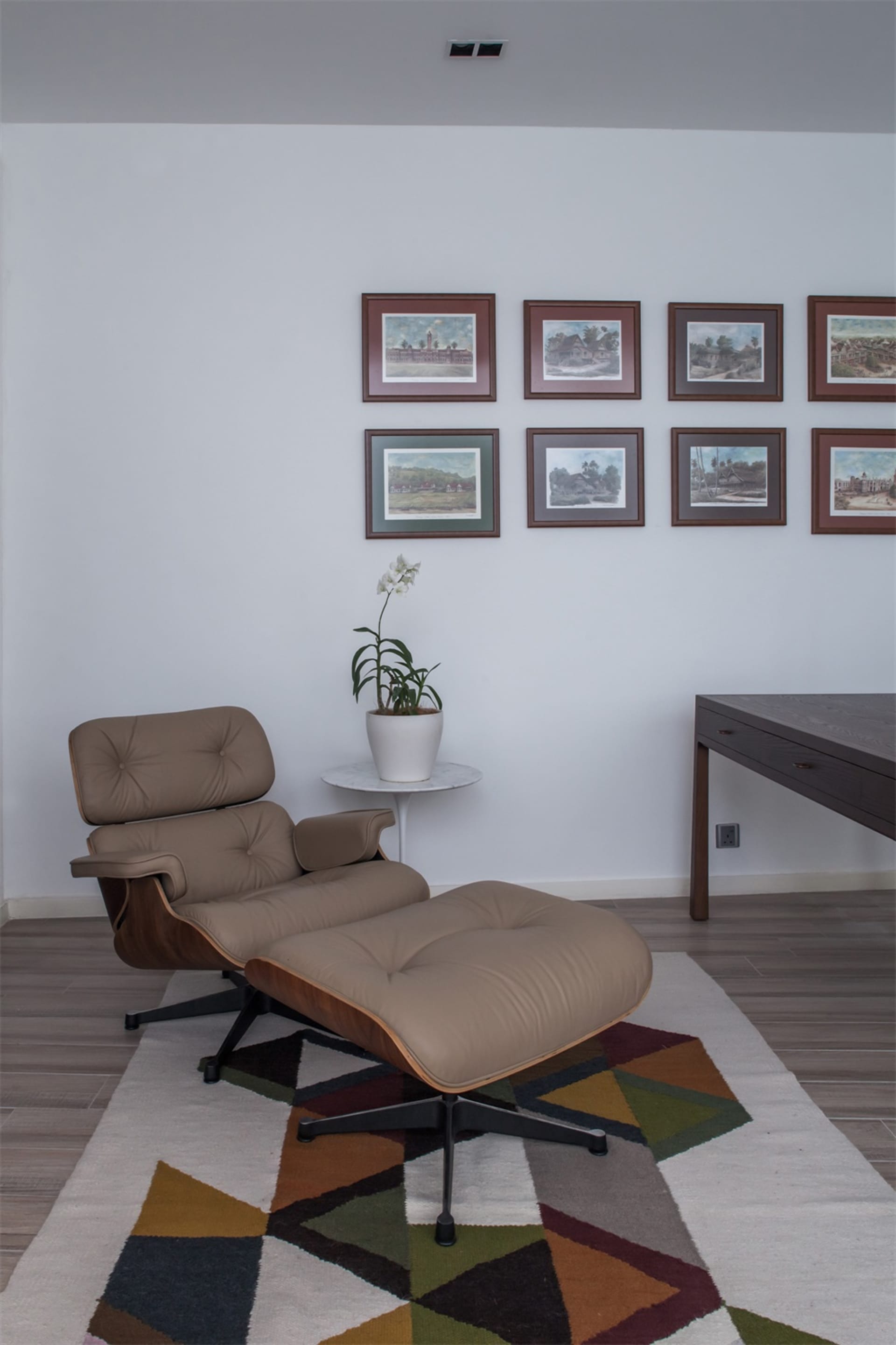 A modern interior lounge featuring a wooden armchair and ottoman with a potted plant.