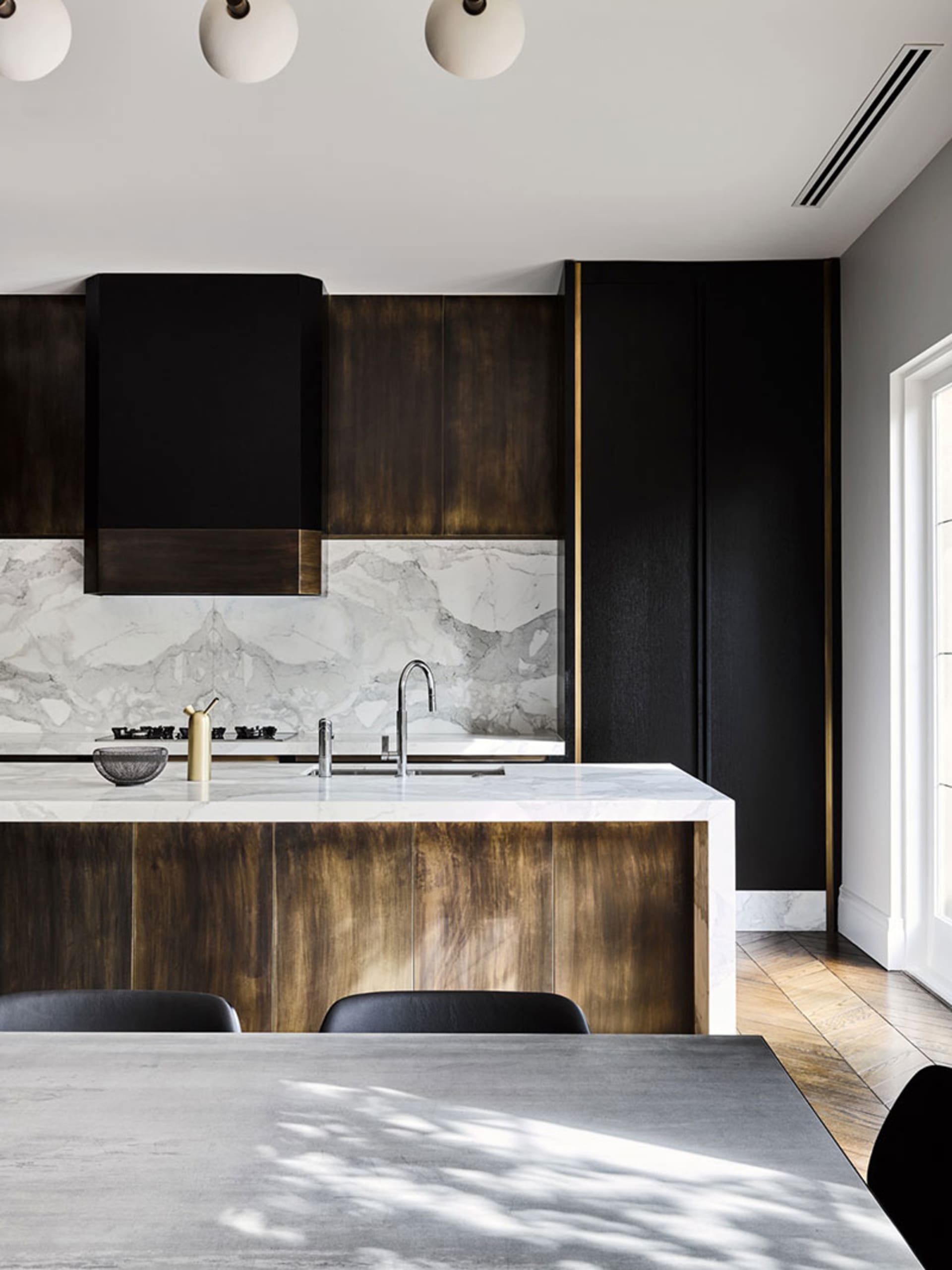Modern kitchen featuring marble countertops, wooden cabinets, and metal accents.