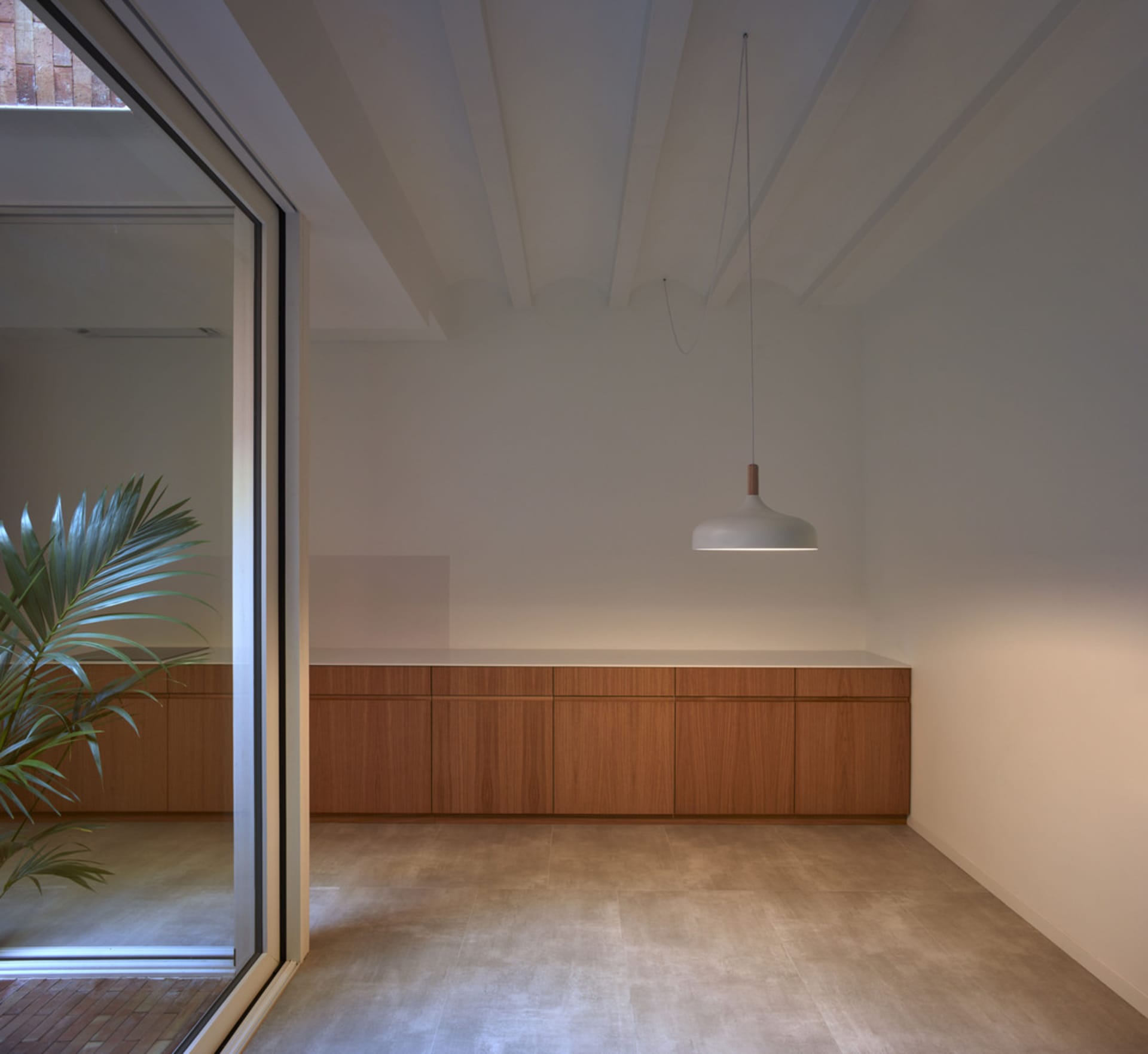 Minimalist residential room with white walls, wooden cabinets, and concrete flooring.