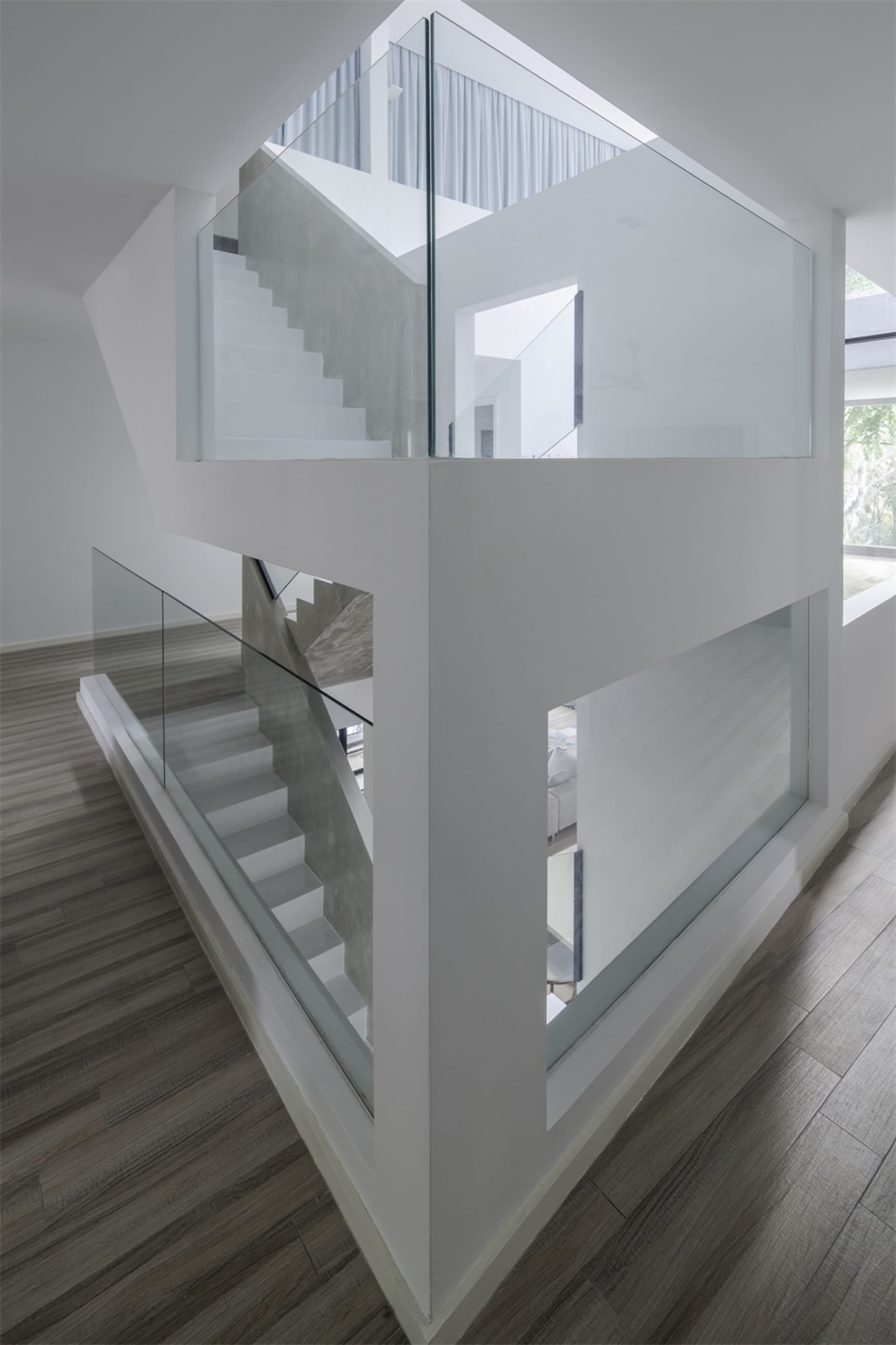 A modern white interior space with glass railings and concrete stairs.