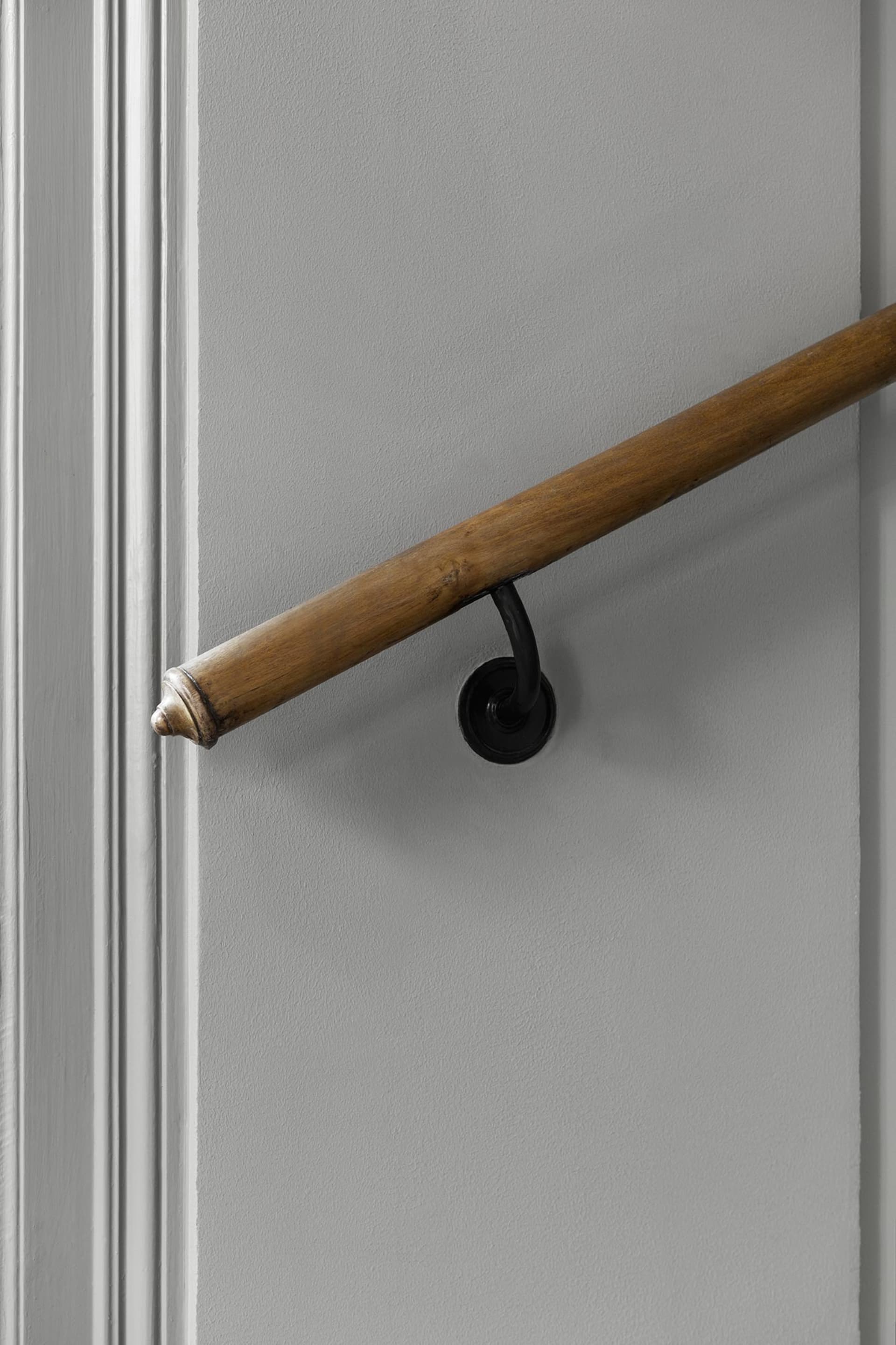 A wooden handrail mounted on a gray wall, providing support in an interior setting.