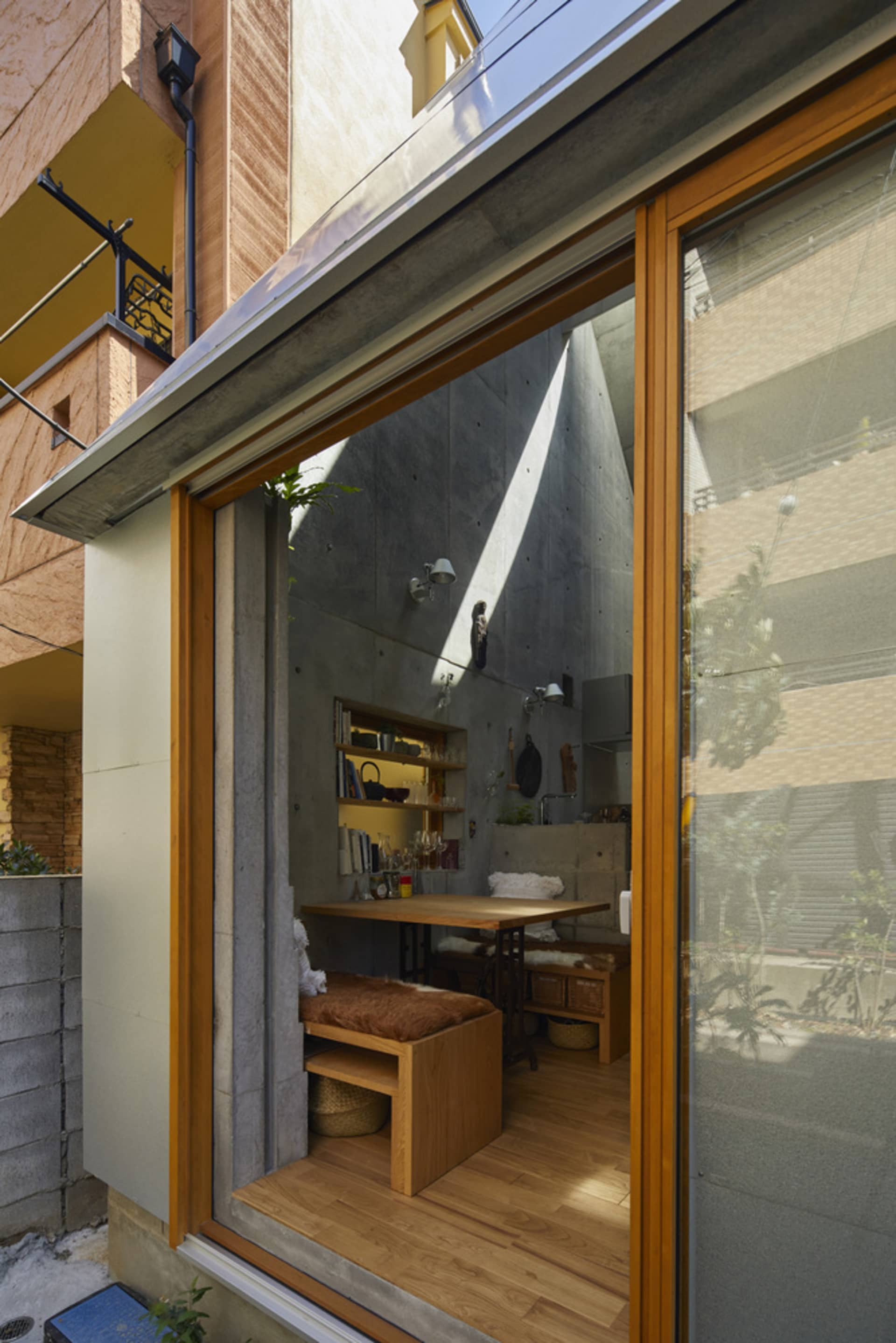 A modern, minimalist kitchen with concrete walls and a small table.
